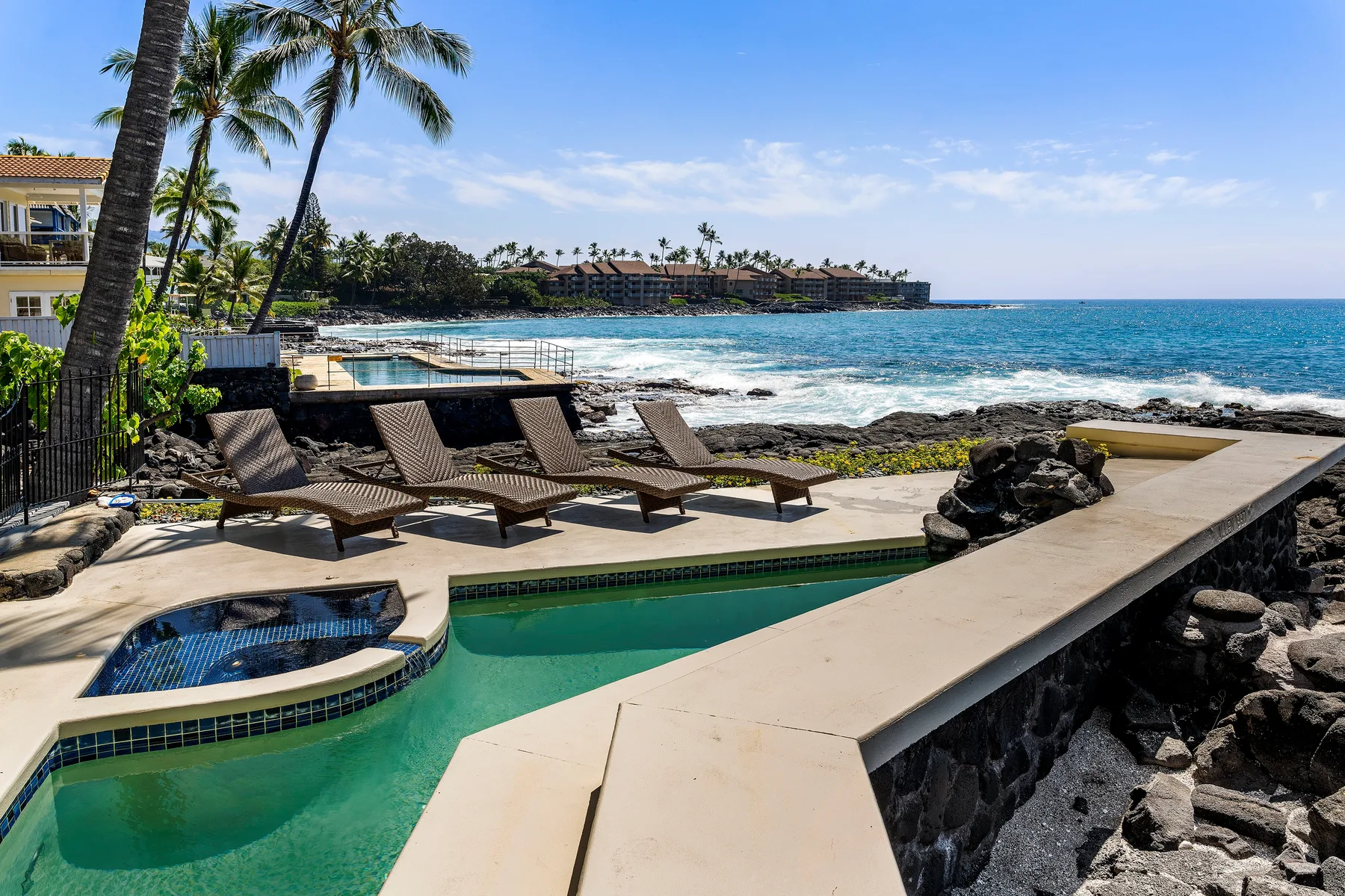 Una piscina y un jacuzzi junto al mar, con asientos reclinables.