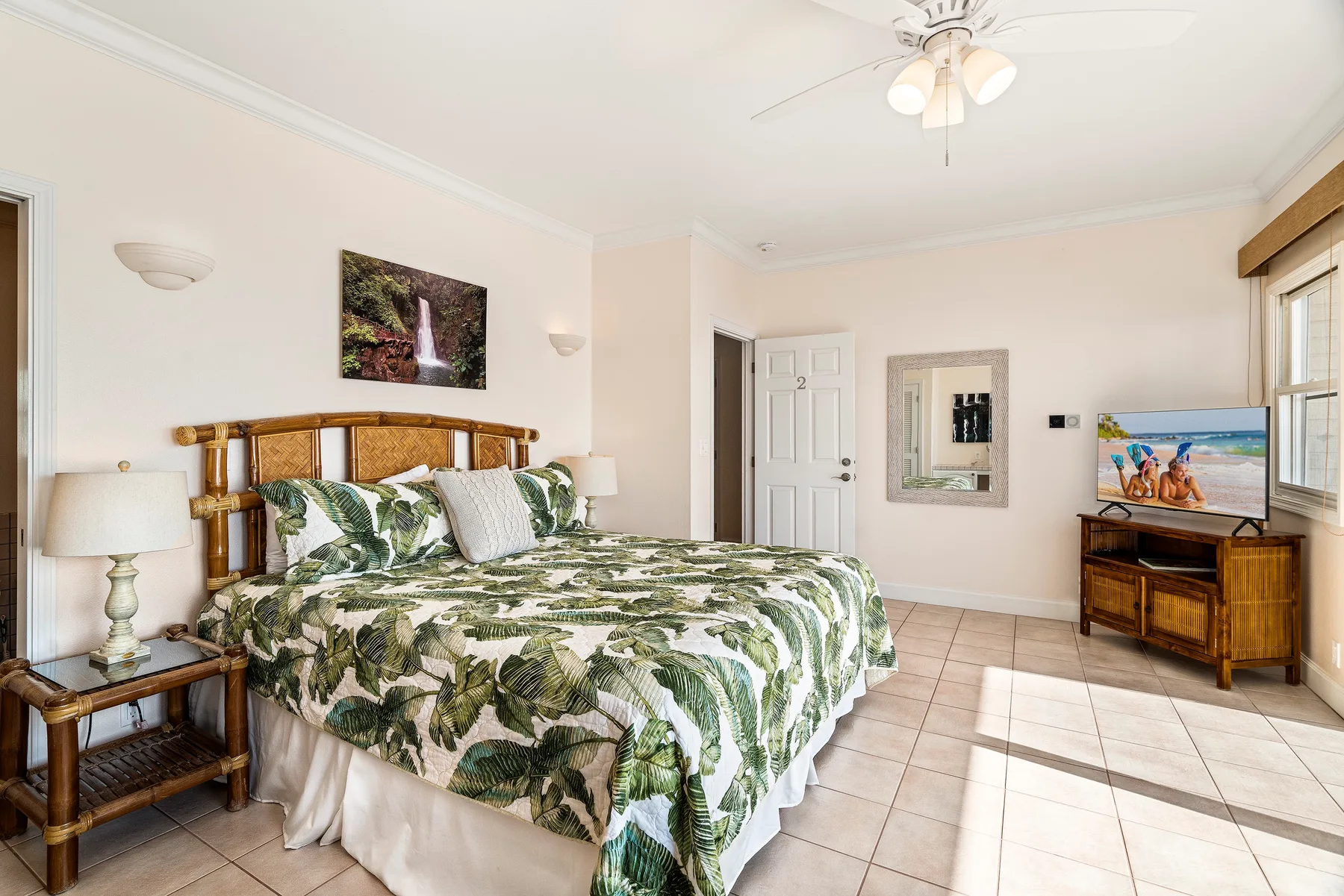 Un dormitorio luminoso con una cama grande cubierta con ropa de cama de hojas verdes.