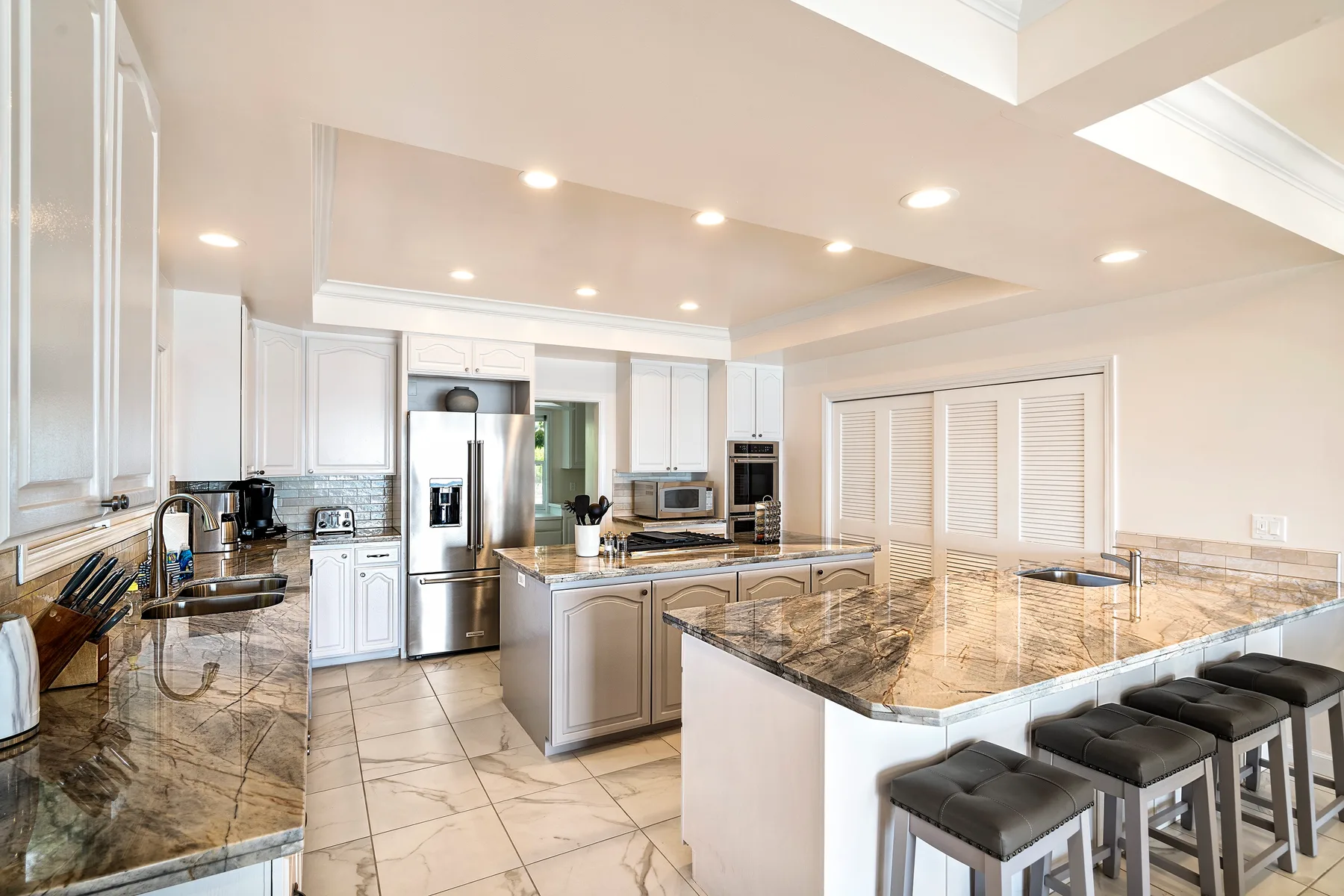 Una cocina luminosa con isla central, electrodomésticos de acero inoxidable y asientos de barra.