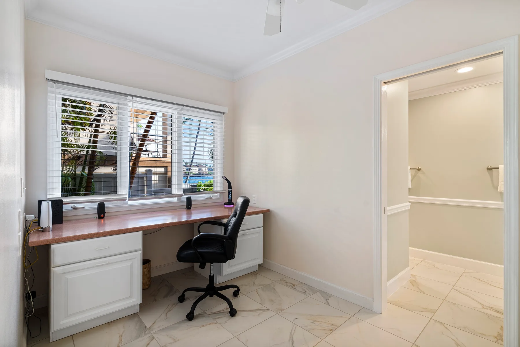 Un espacio de trabajo luminoso con un escritorio junto a una ventana y una puerta abierta.