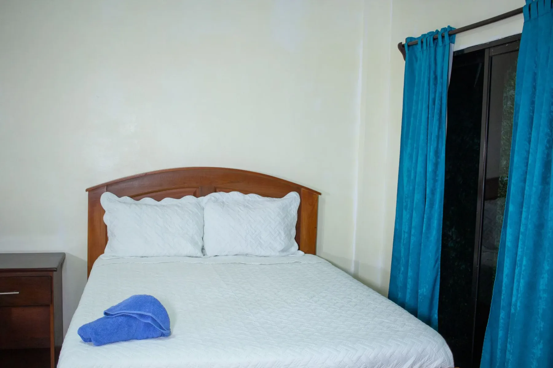 Dormitorio con cama y cortinas turquesas