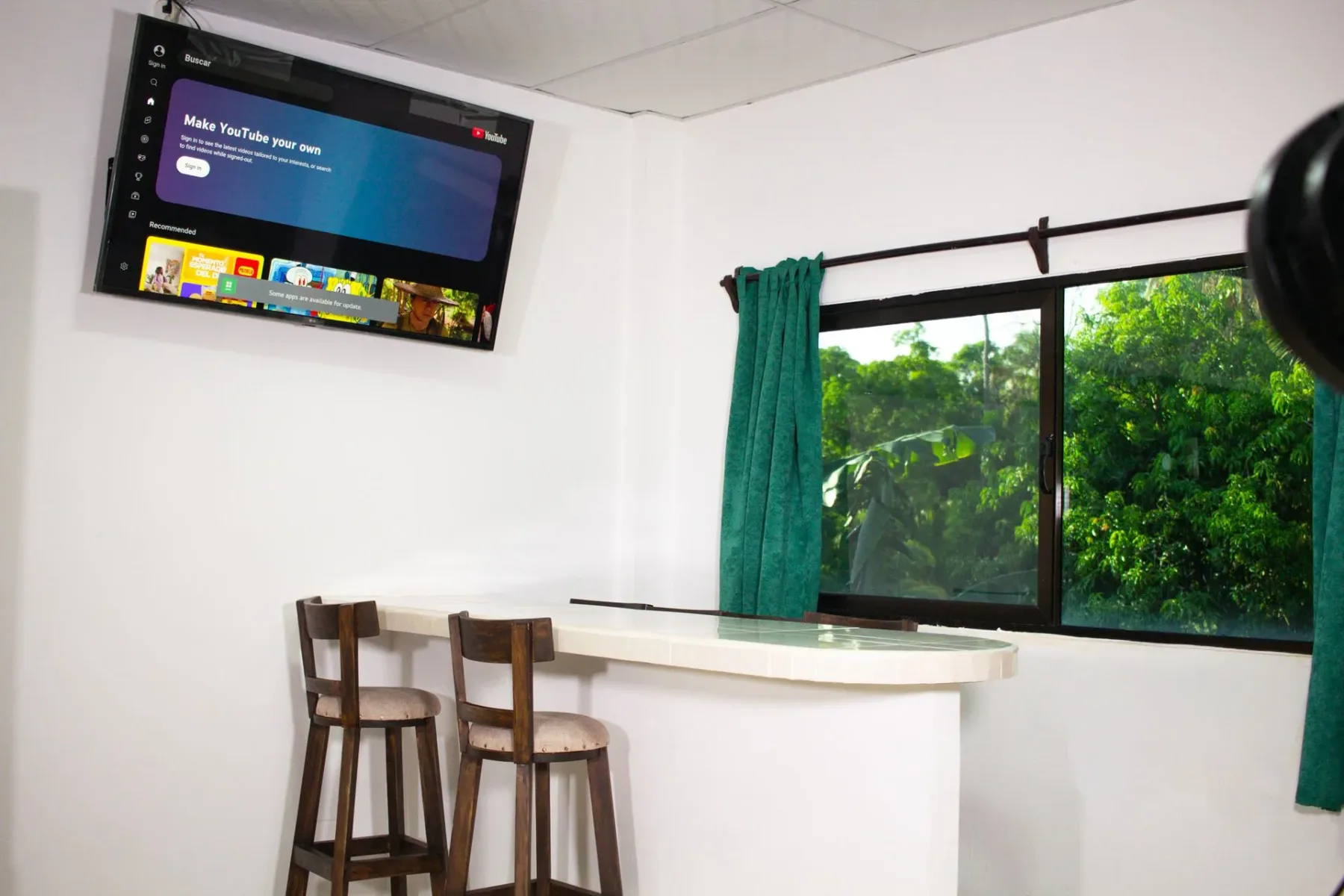 Espacio interior con televisor, barra y bancos altos