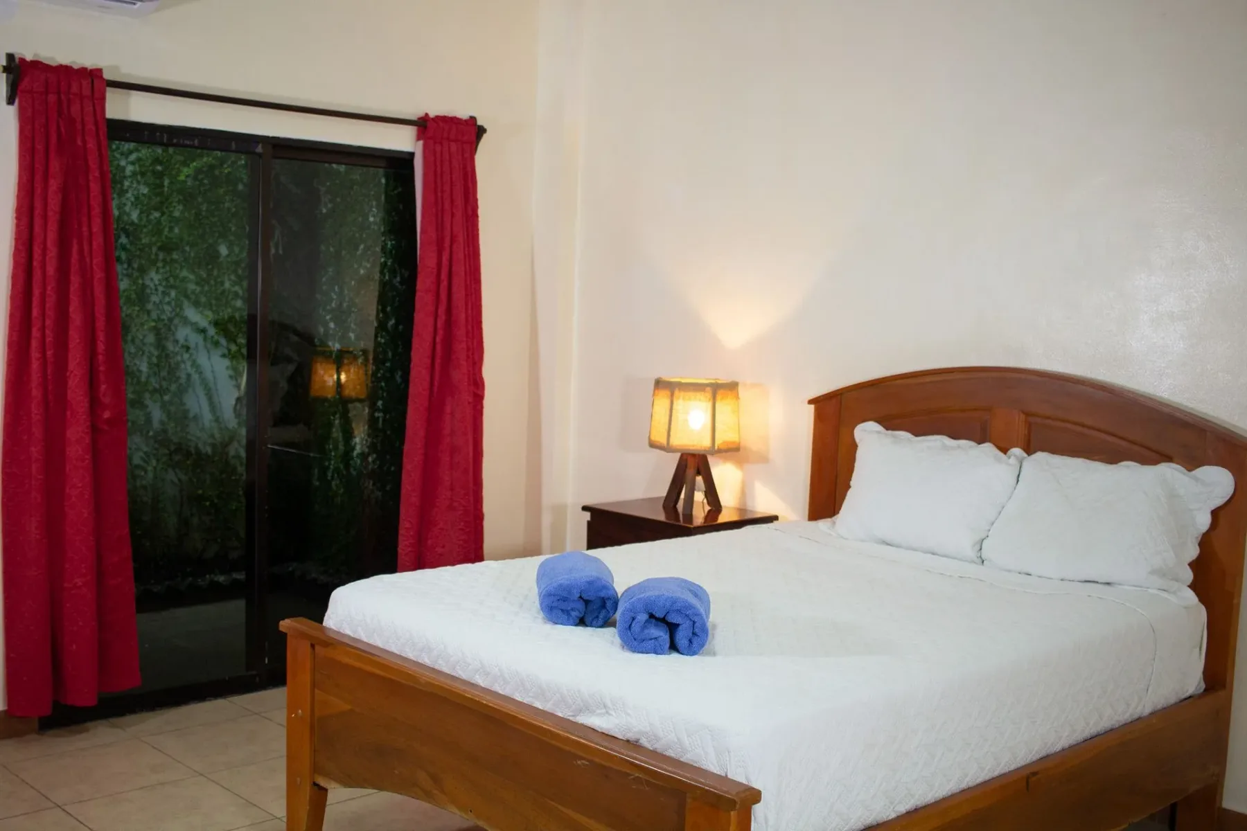 Dormitorio con cama doble y cortinas rojas
