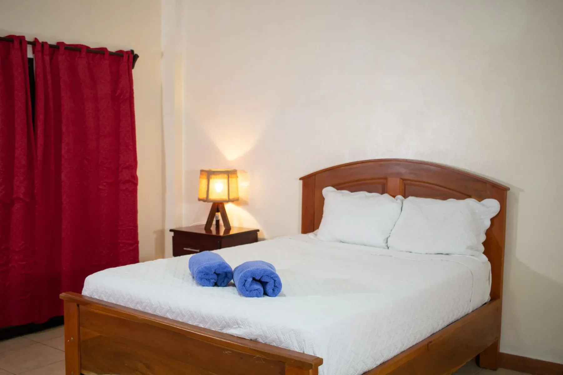 Dormitorio con cama de madera y cortinas rojas