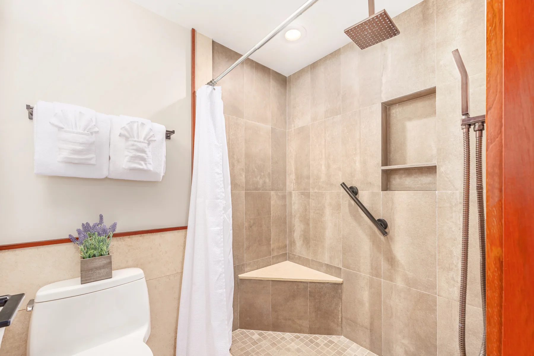 A tiled bathroom with a shower, wall niche, and towel rack.
