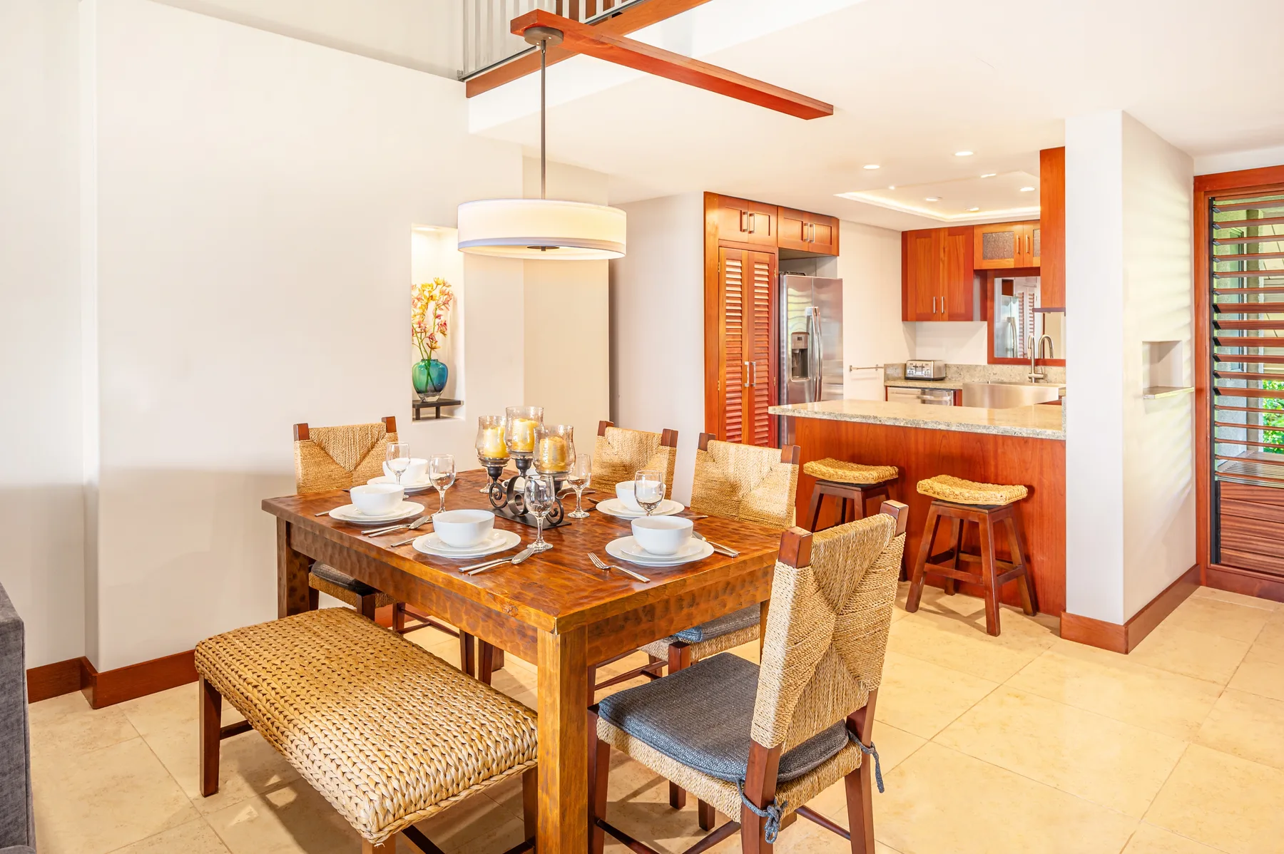 A dining area with a wooden table set beside an open kitchen.