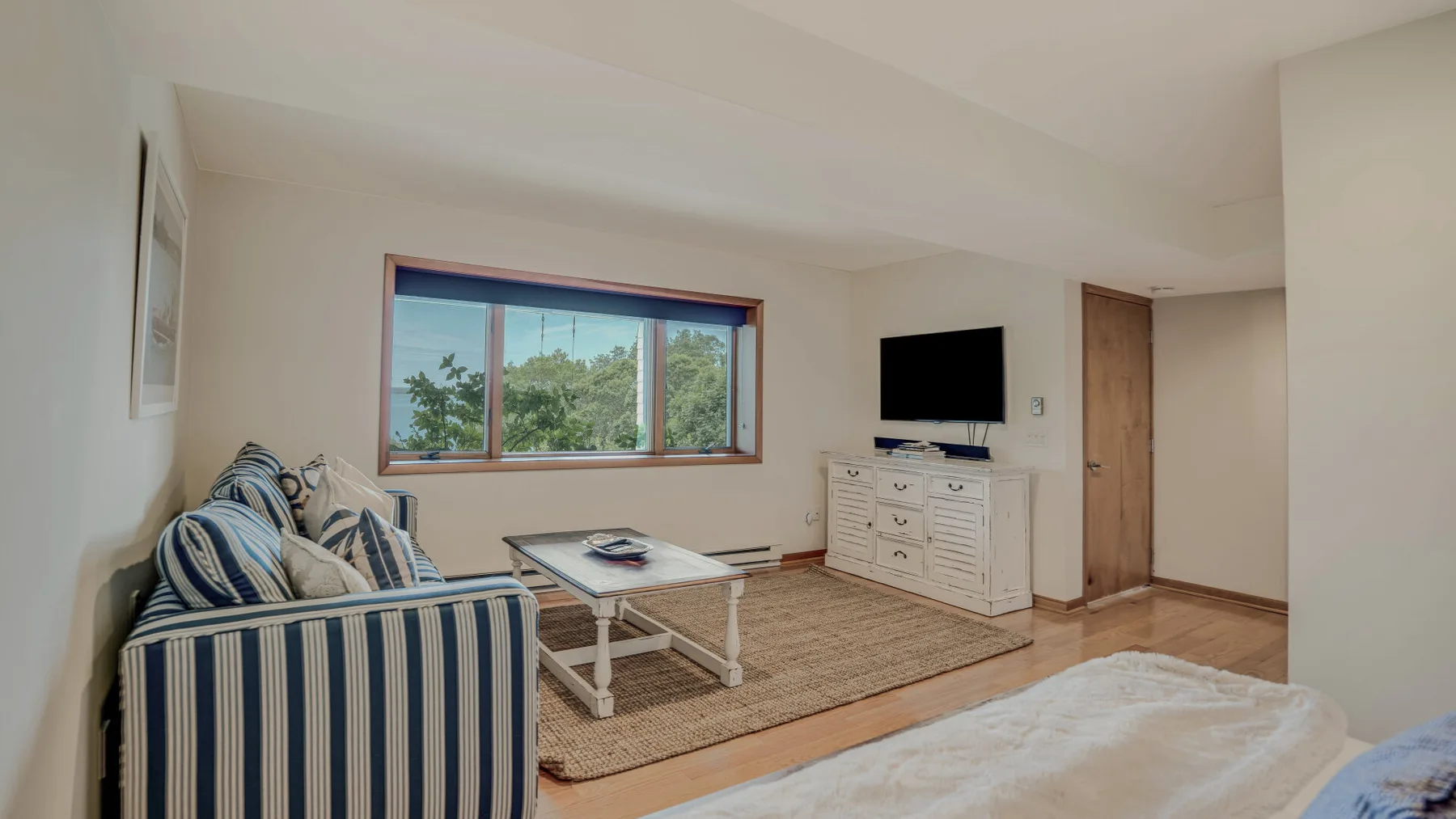 A living room with striped seating, a coffee table, and a television.