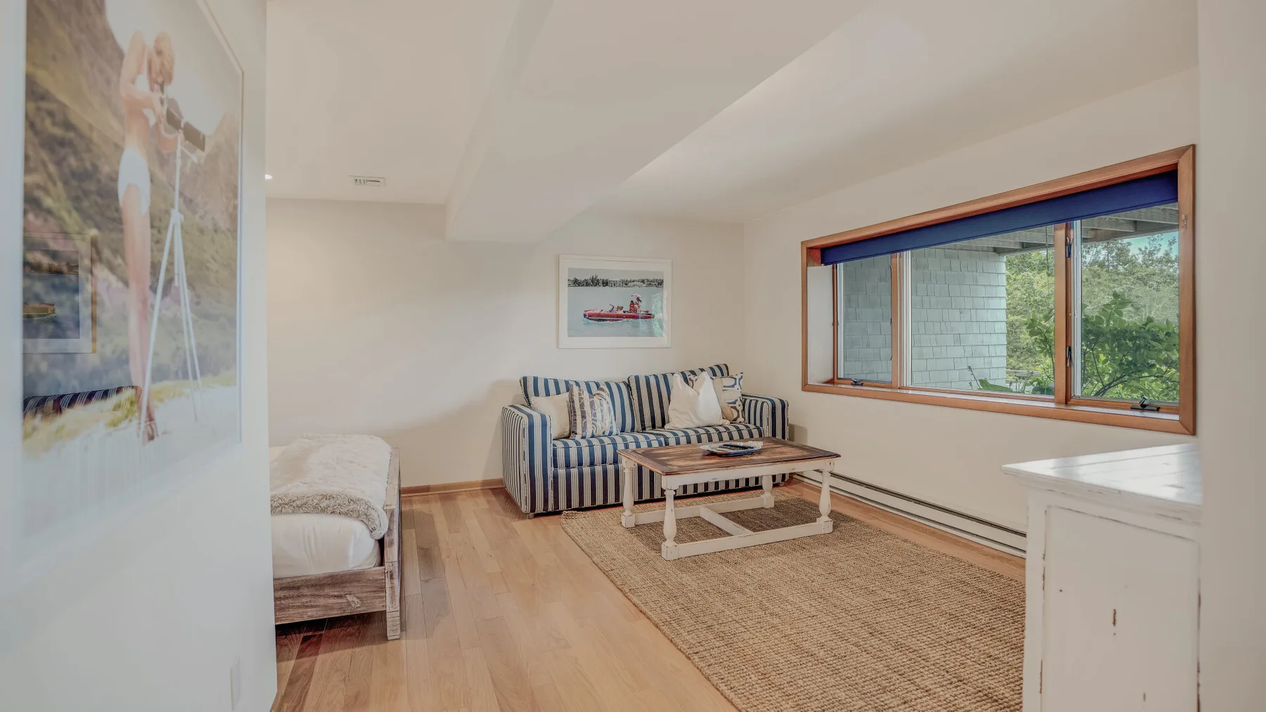 A bright living room with striped seating, a coffee table, and a large window.