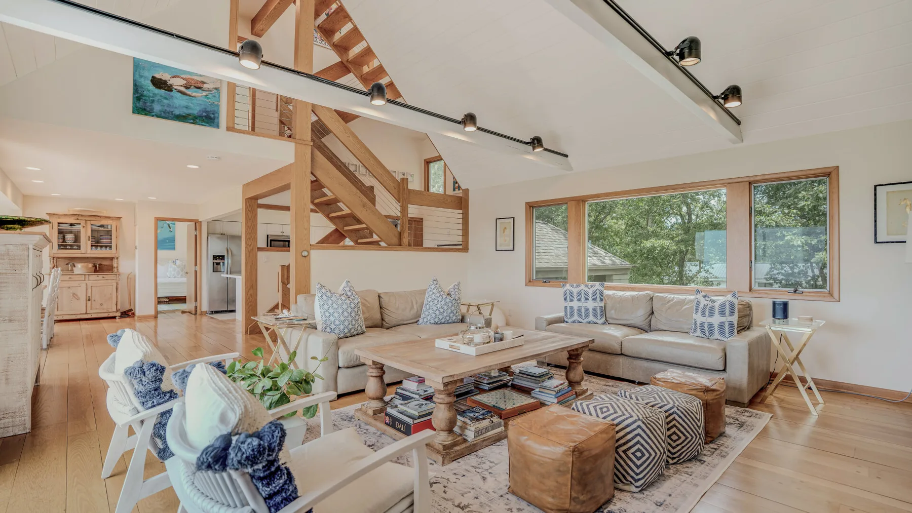 A bright living room with seating, a coffee table, and large windows.