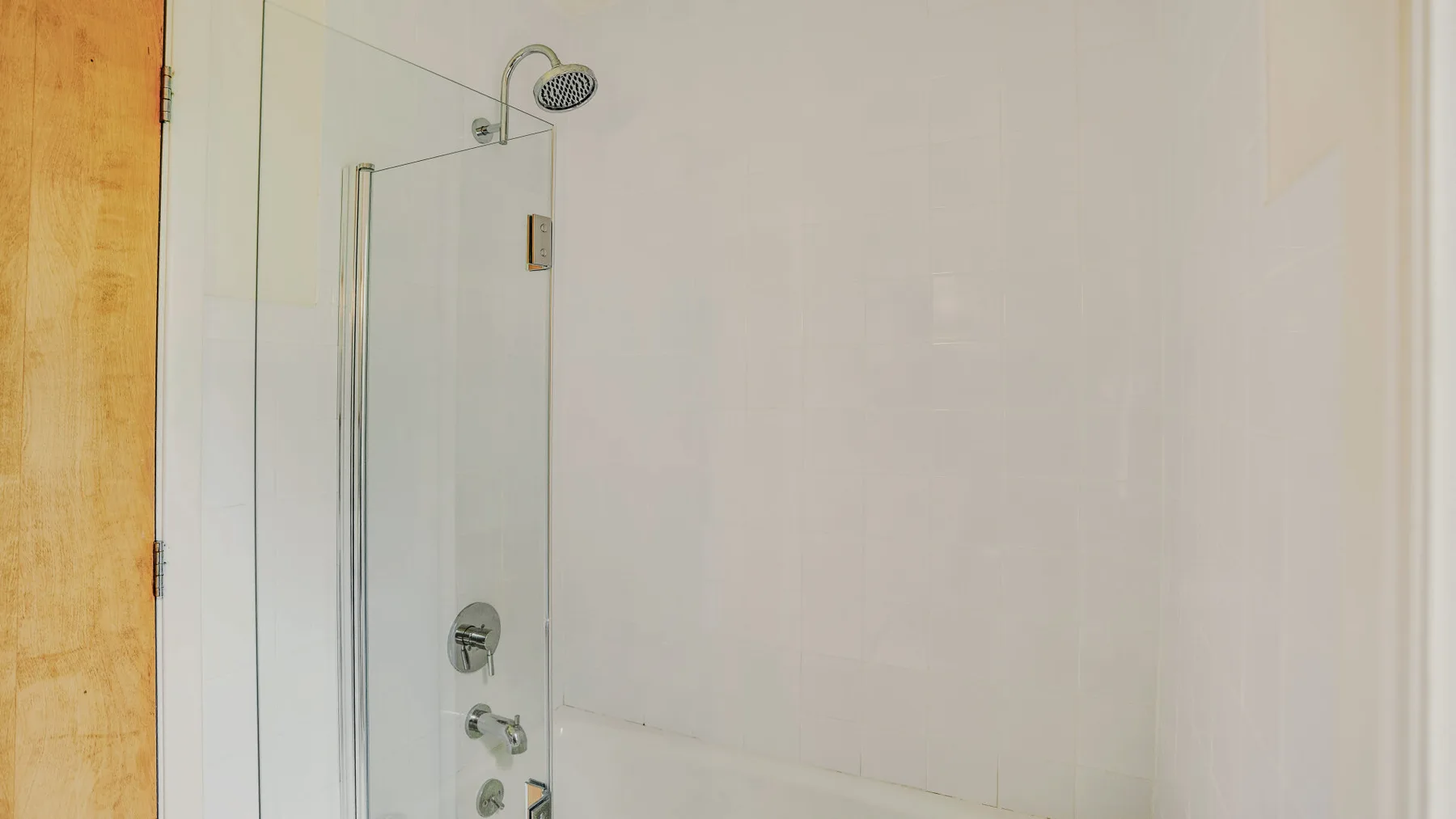 A tiled bathroom shower with a glass screen and metal fixtures.