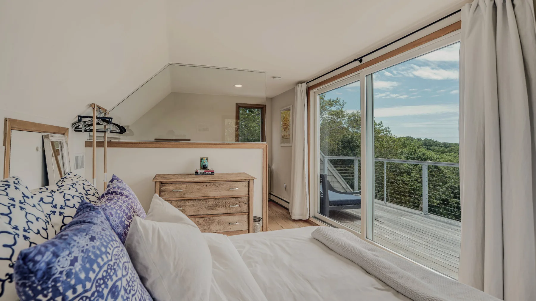 A bedroom with a bed beside large sliding glass doors opening onto a balcony.