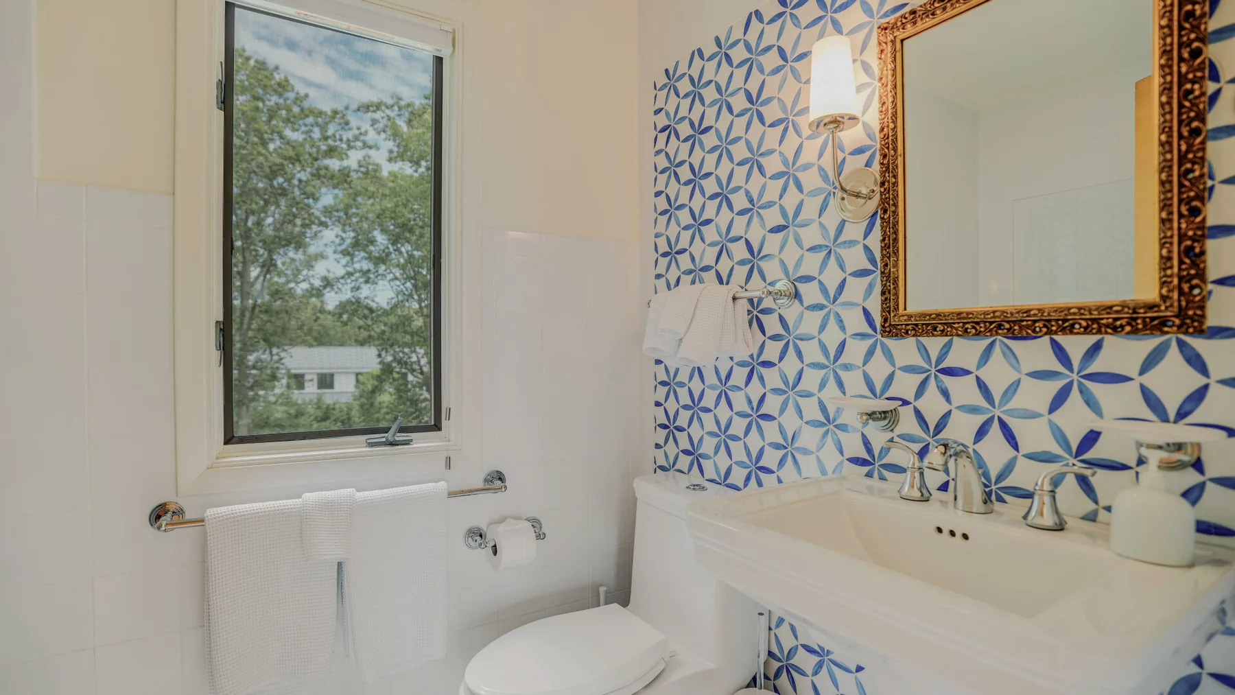A bathroom with a sink, mirror, and blue patterned tile.