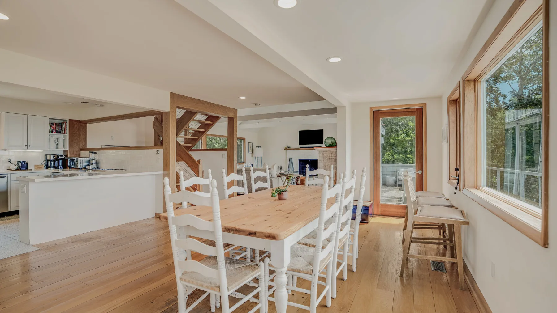 An open dining and kitchen area with a wooden table and large windows.