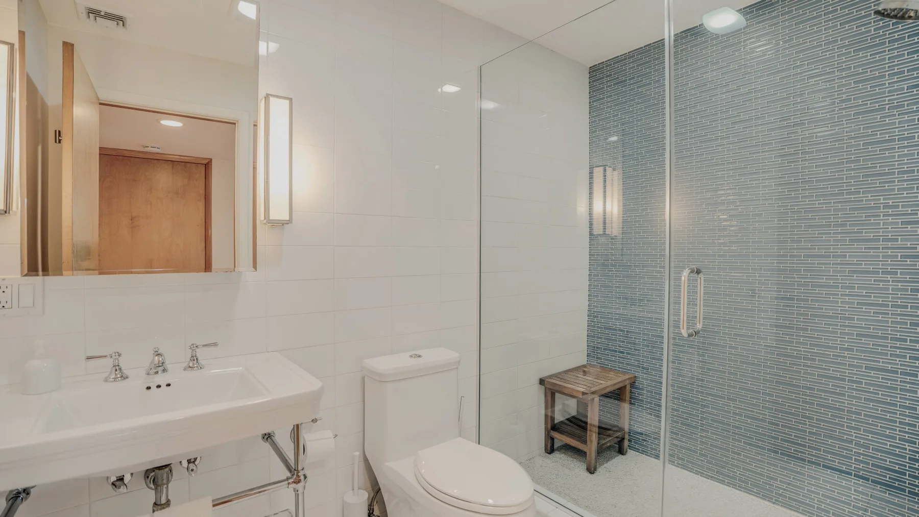 A bright bathroom with a sink, toilet, and glass shower.