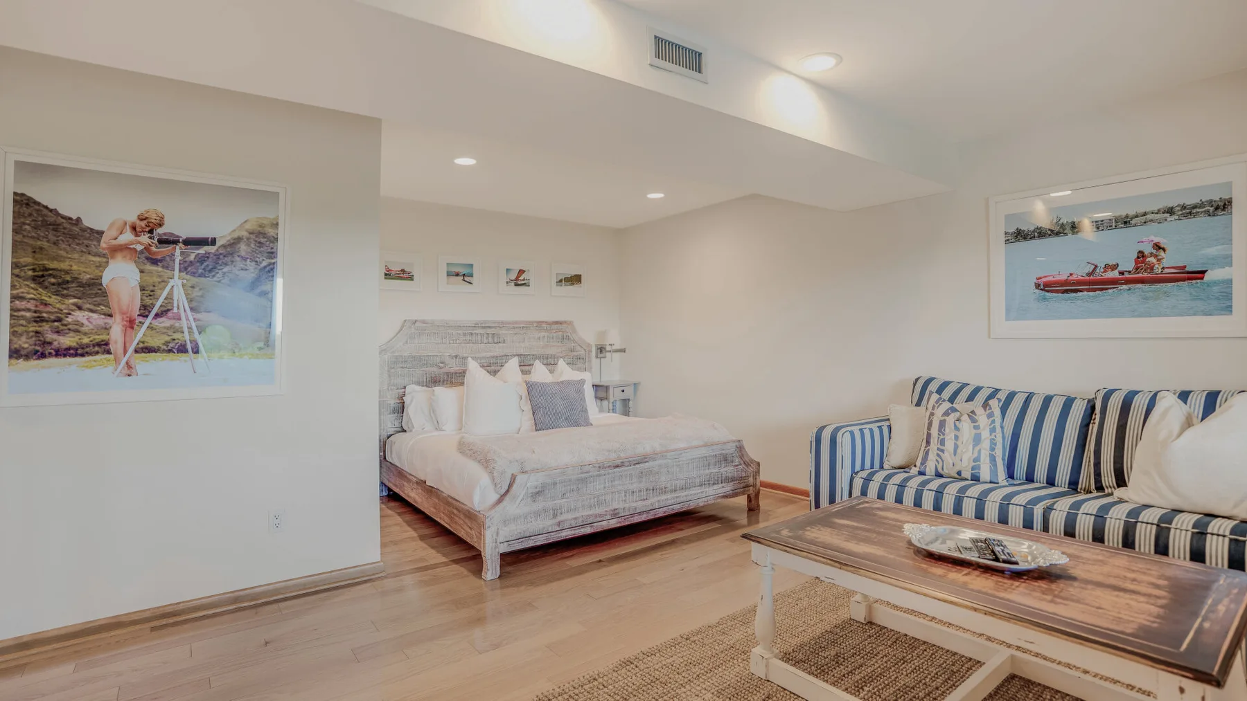 A bright bedroom and sitting area with a bed, striped seating, and a coffee table.