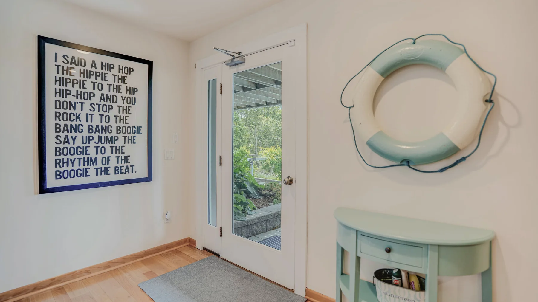 A bright entryway with a glass-paneled door and a framed poster on the wall.