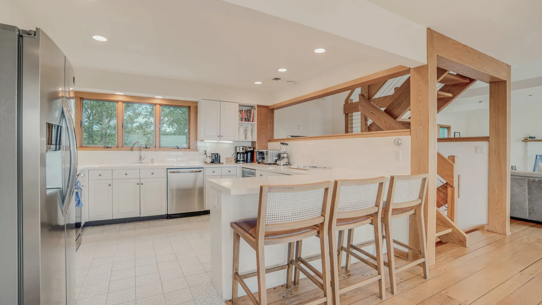 A bright kitchen with a central island and wooden bar seating.