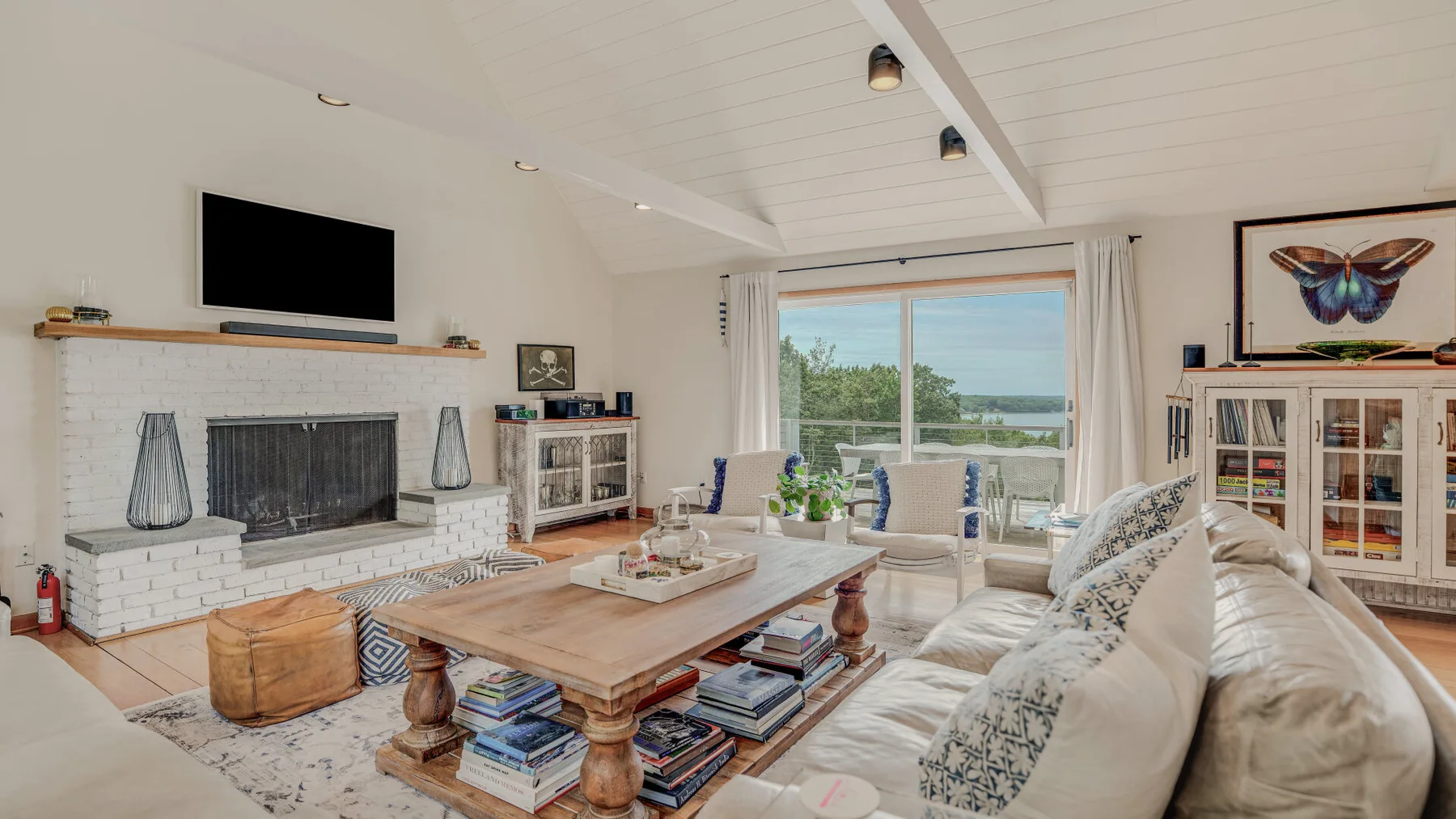 Una sala luminosa con chimenea, asientos y una gran ventana con vistas a la vegetación.