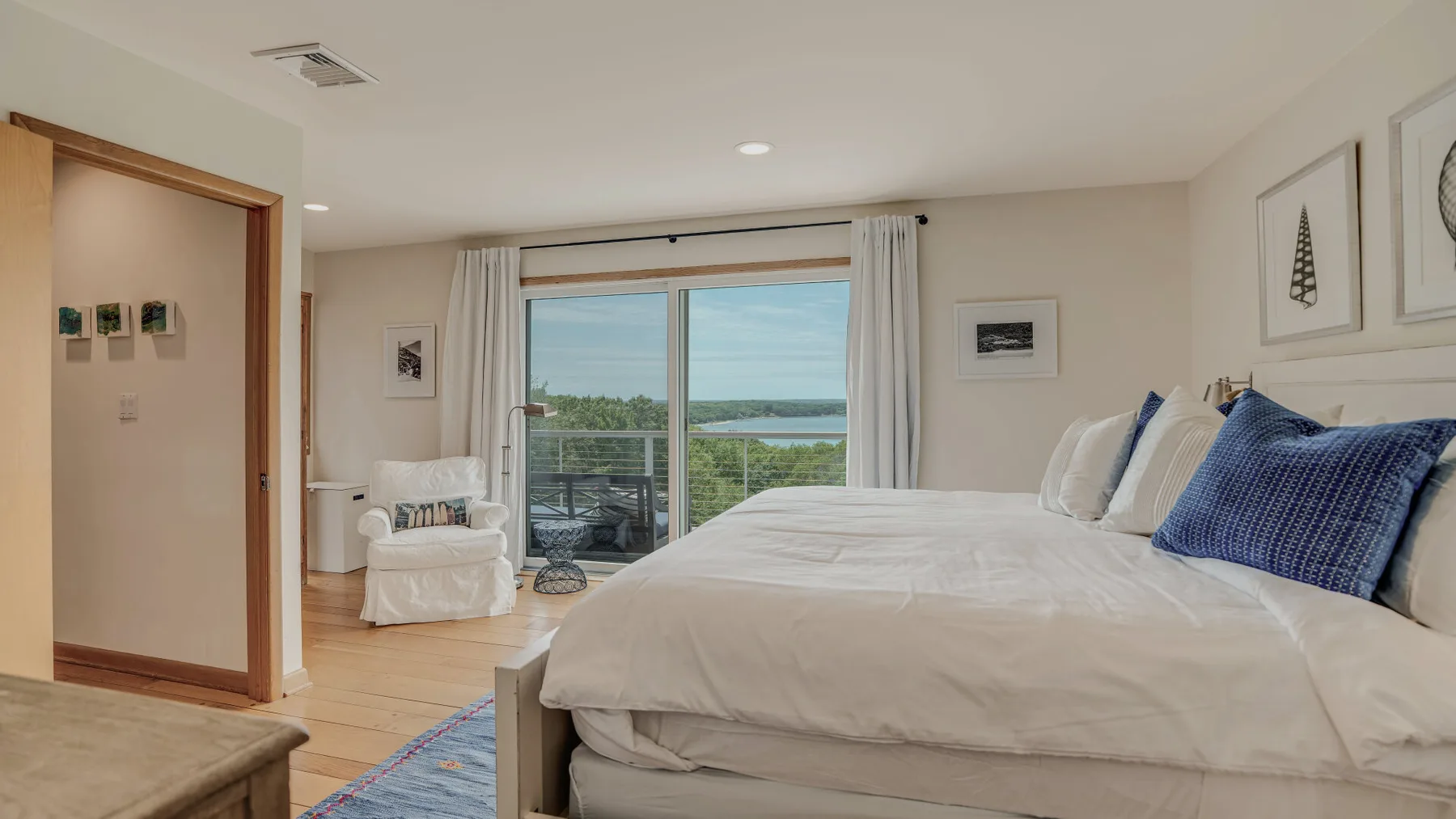 A bright bedroom with a large bed and sliding glass doors opening onto a balcony.