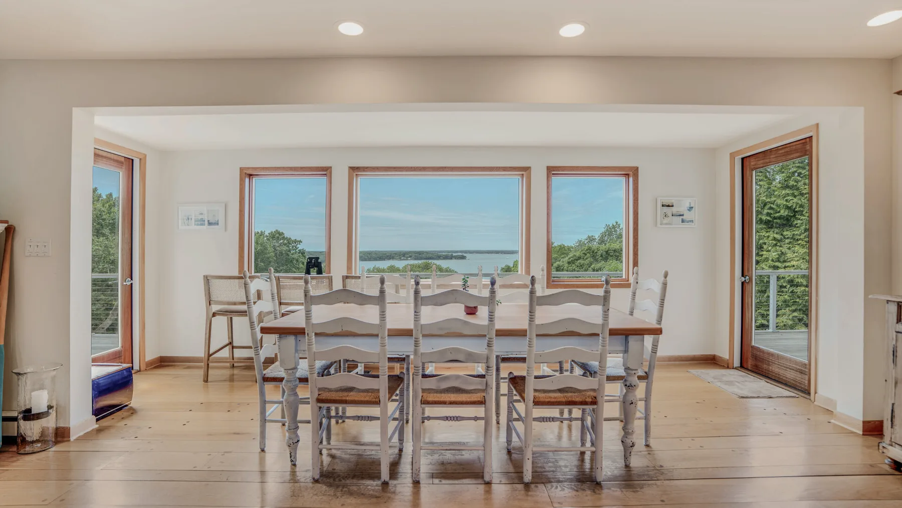 A dining area with a long table and chairs beside large windows.