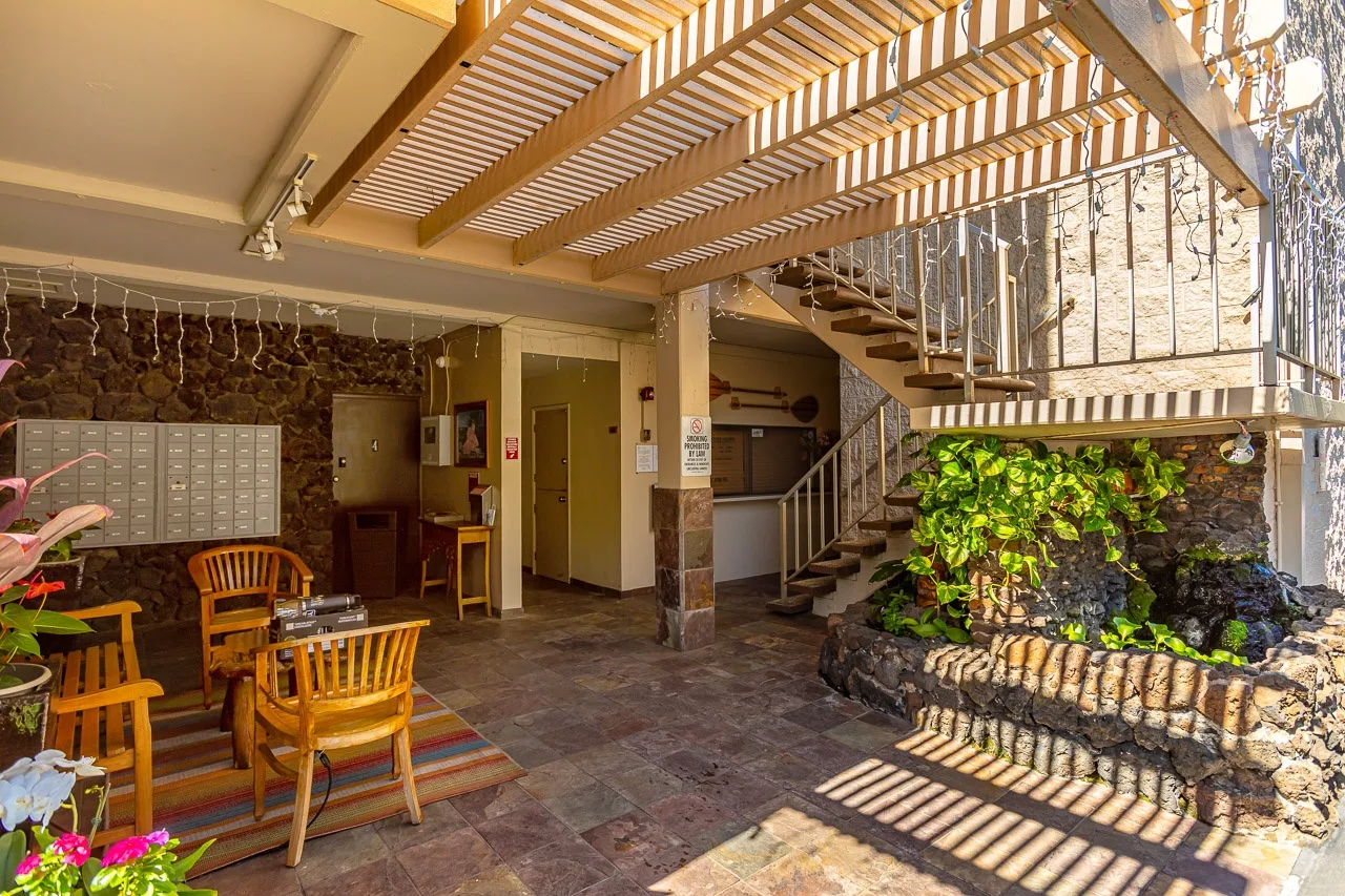 Un patio cubierto con asientos, una escalera y un jardín rocoso con plantas.