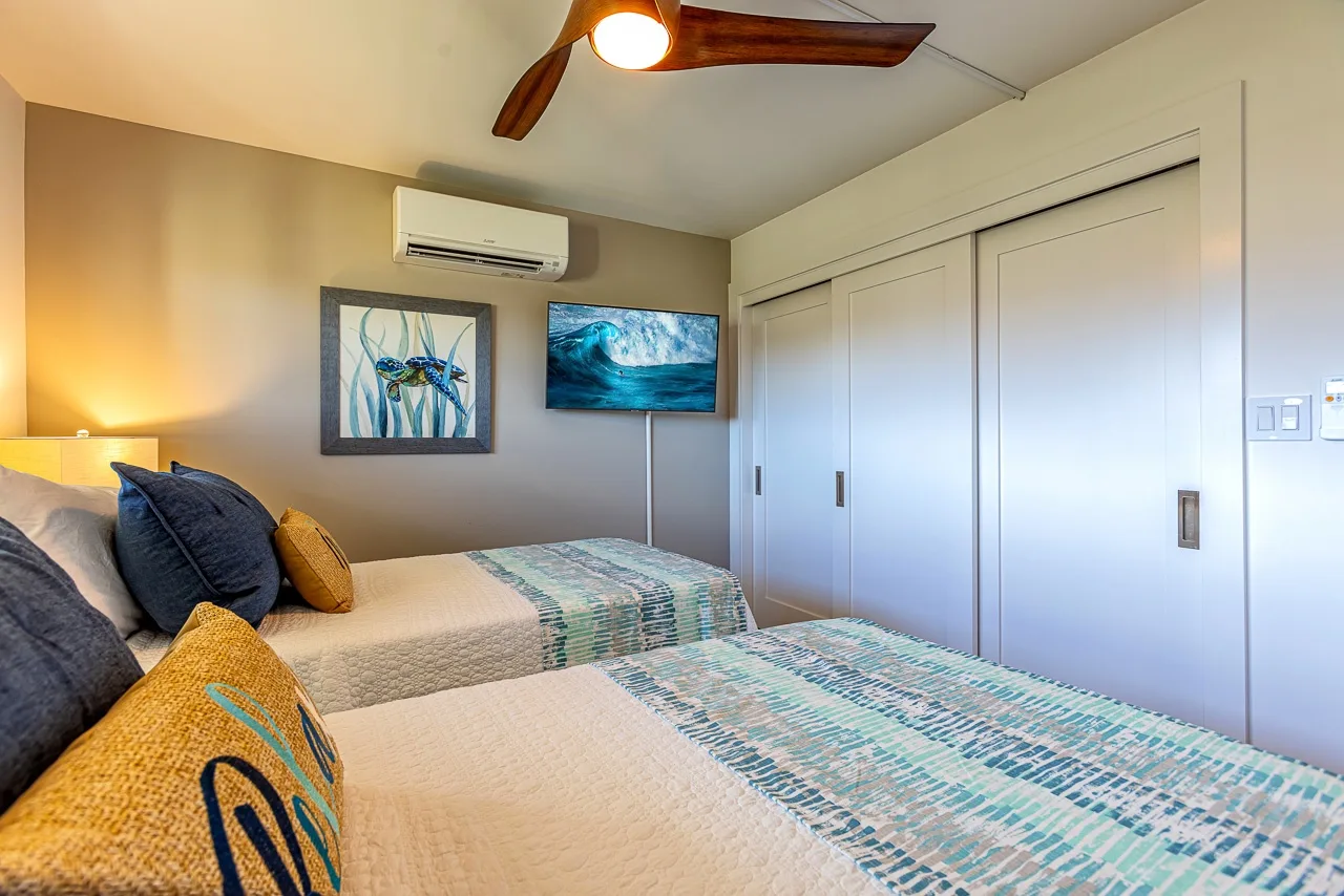 Un dormitorio con dos camas, ropa de cama estampada y puertas corredizas de armario.