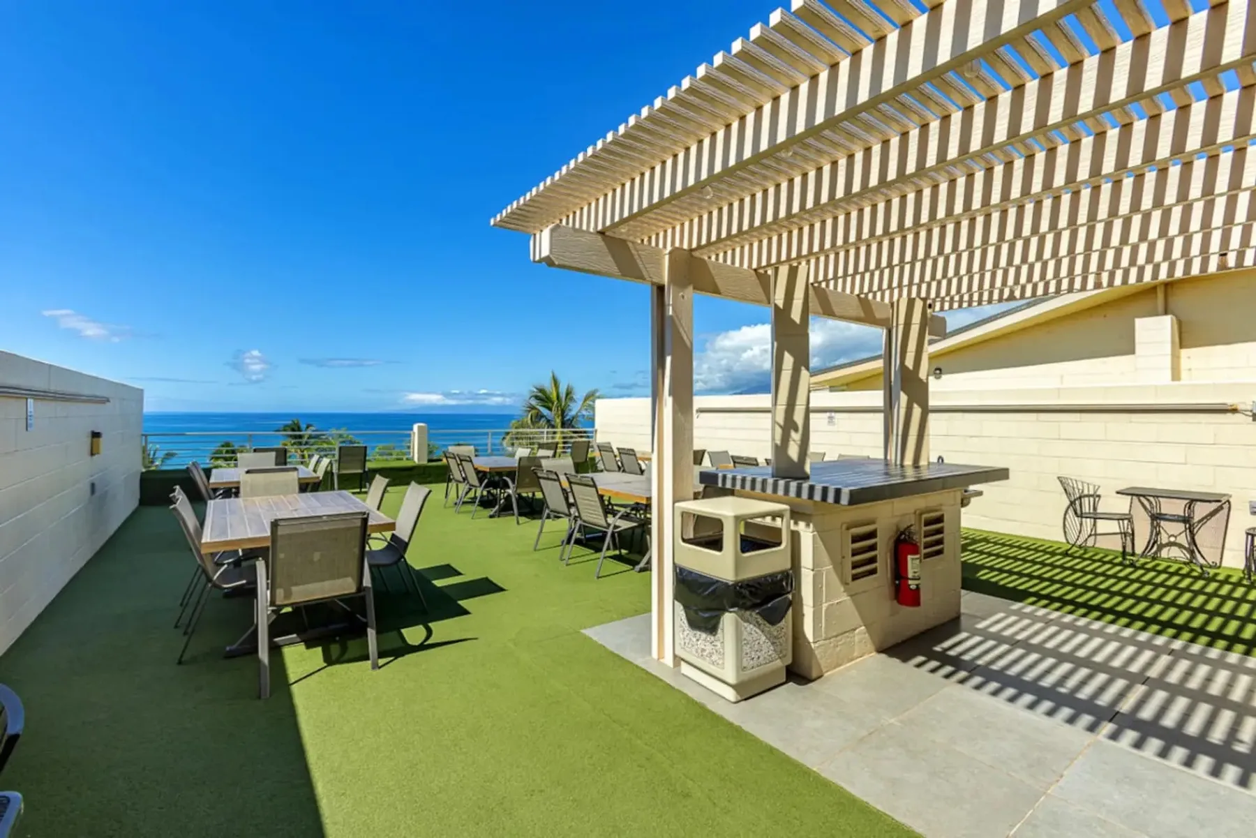 Una terraza en la azotea con asientos al aire libre, una parrilla y vistas al mar.