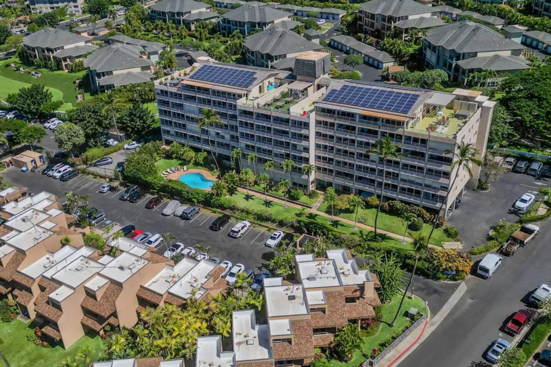 Vista aérea de un edificio de varias plantas con paneles solares y una piscina.