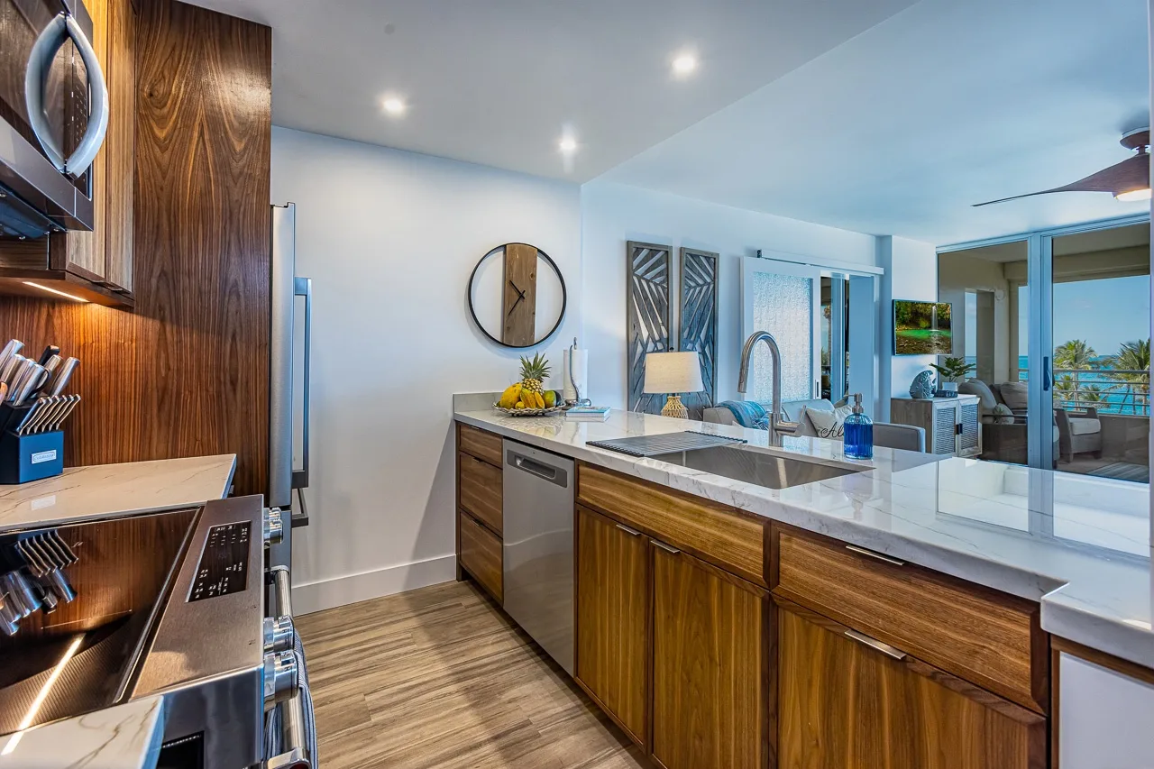 Una cocina moderna con gabinetes de madera, una isla central y vista a la sala de estar.