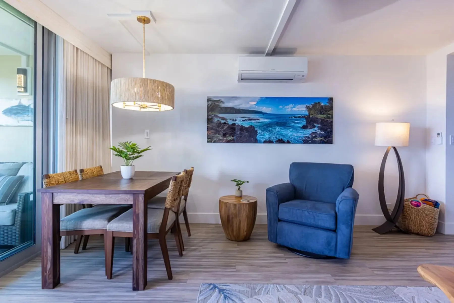 Una sala de estar con un sillón azul y una mesa de comedor junto a una puerta de vidrio.