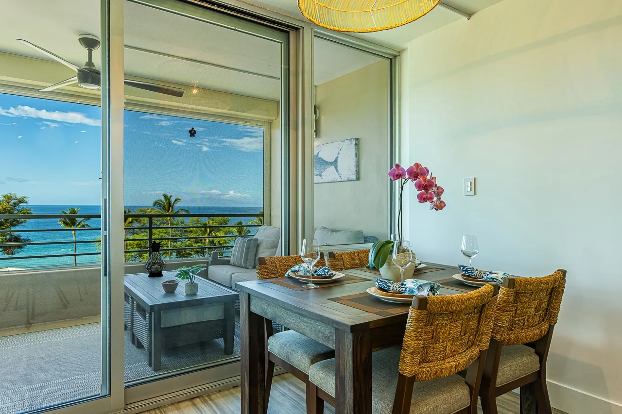 Un comedor junto a puertas de vidrio da a un balcón con vistas al mar.