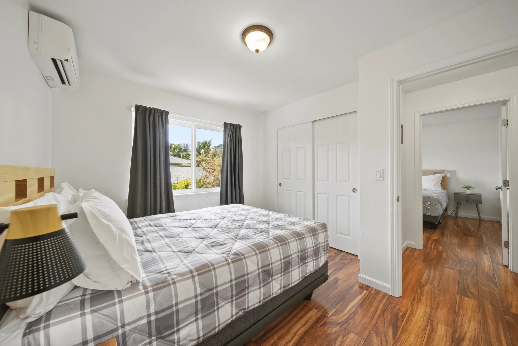 A bedroom with a bed, a window with curtains, and closet doors.