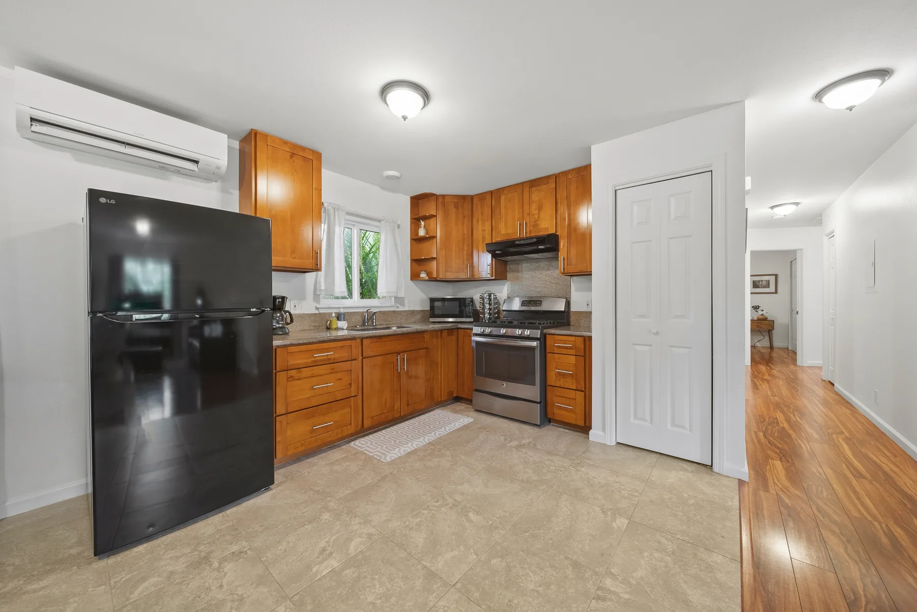 A kitchen with wooden cabinets, a black refrigerator, and an oven.