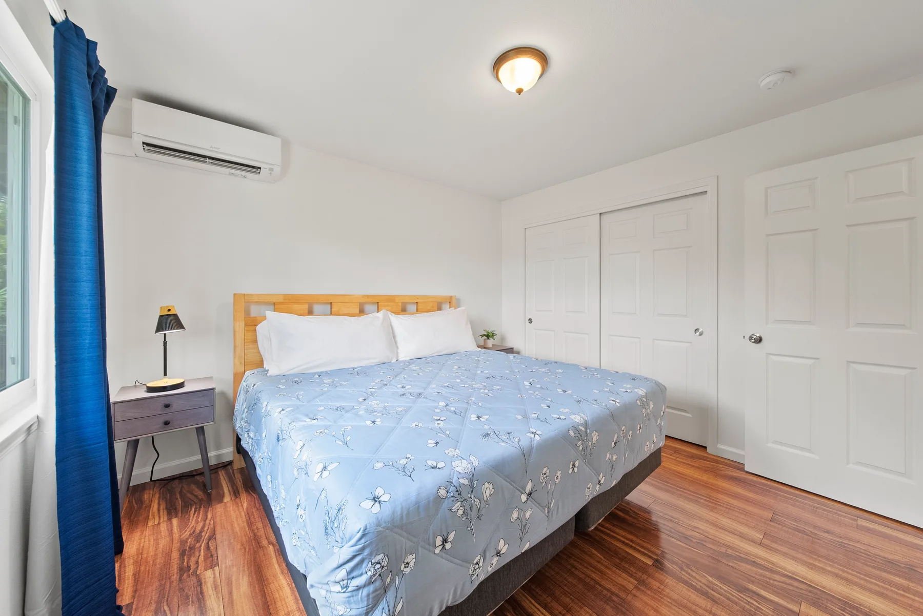 A bedroom with a bed covered in a blue floral bedspread.