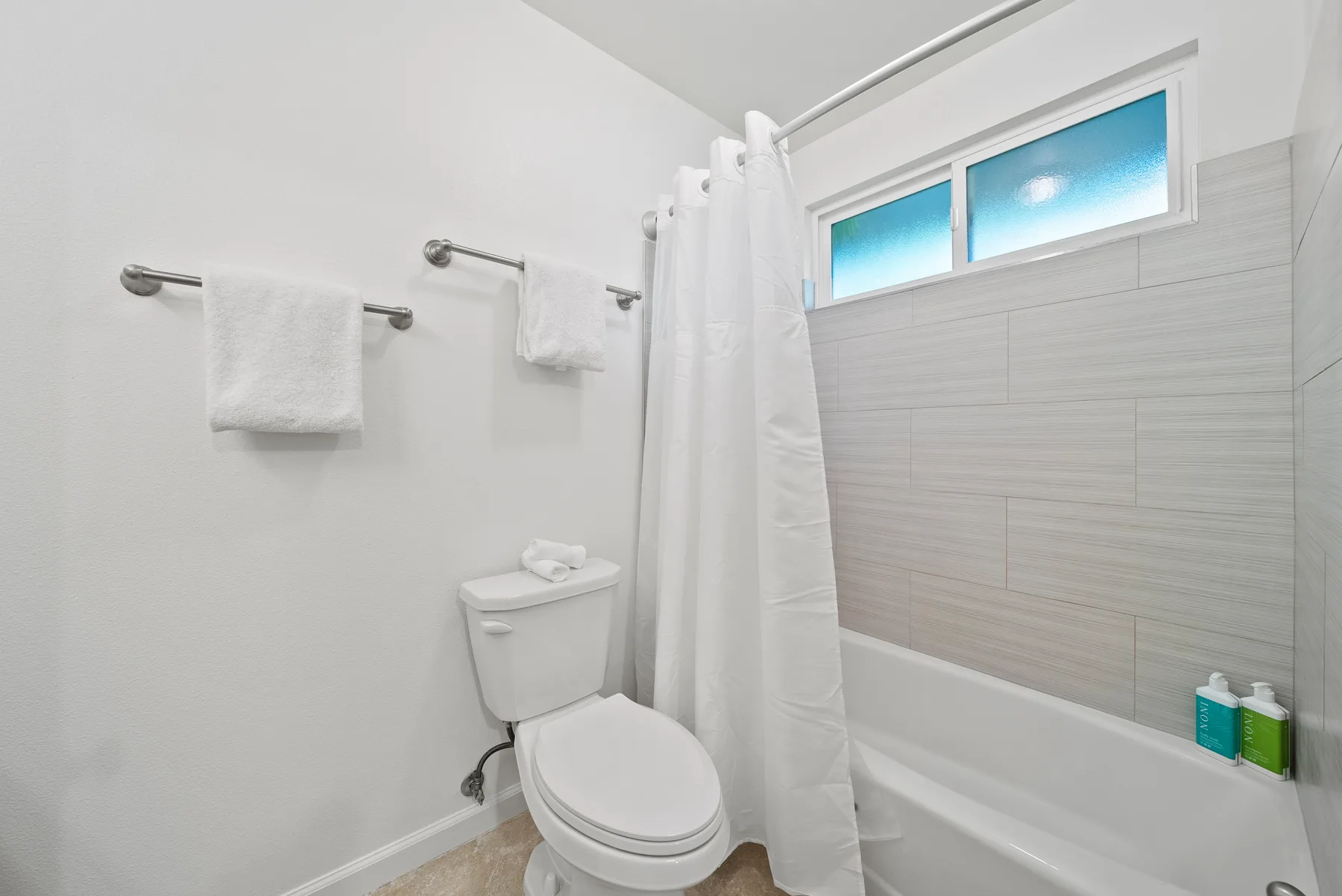 A bathroom with a toilet, bathtub, and white shower curtain.