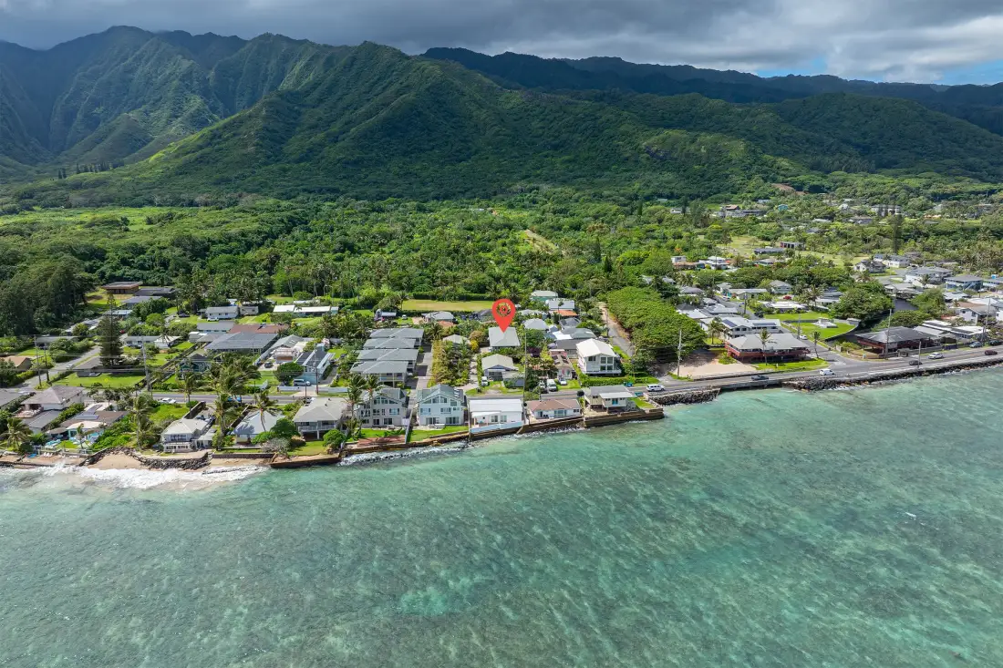 An aerial view of a coastal neighborhood with green mountains in the background.