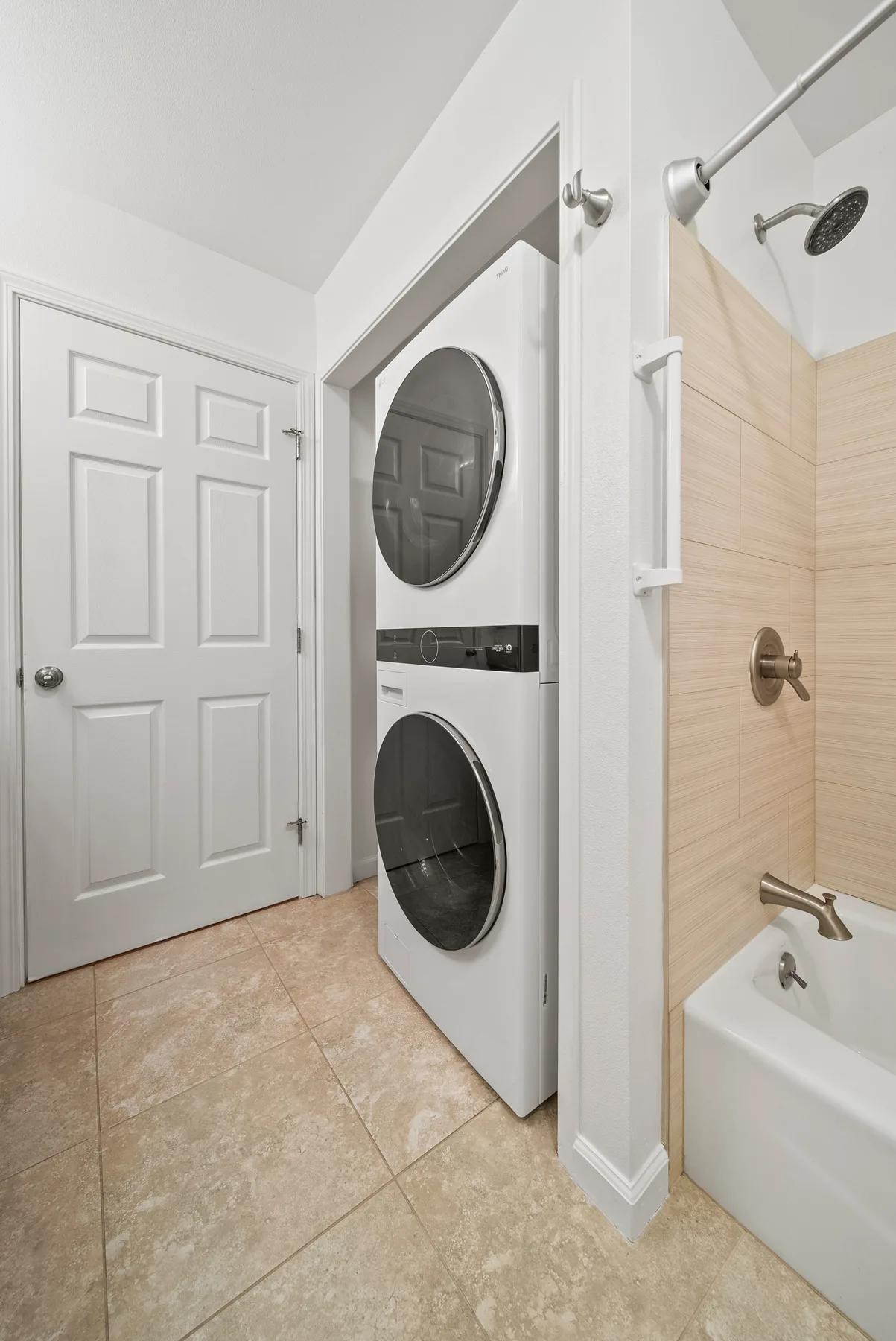 A bright bathroom with a washer and dryer beside the shower and bathtub.