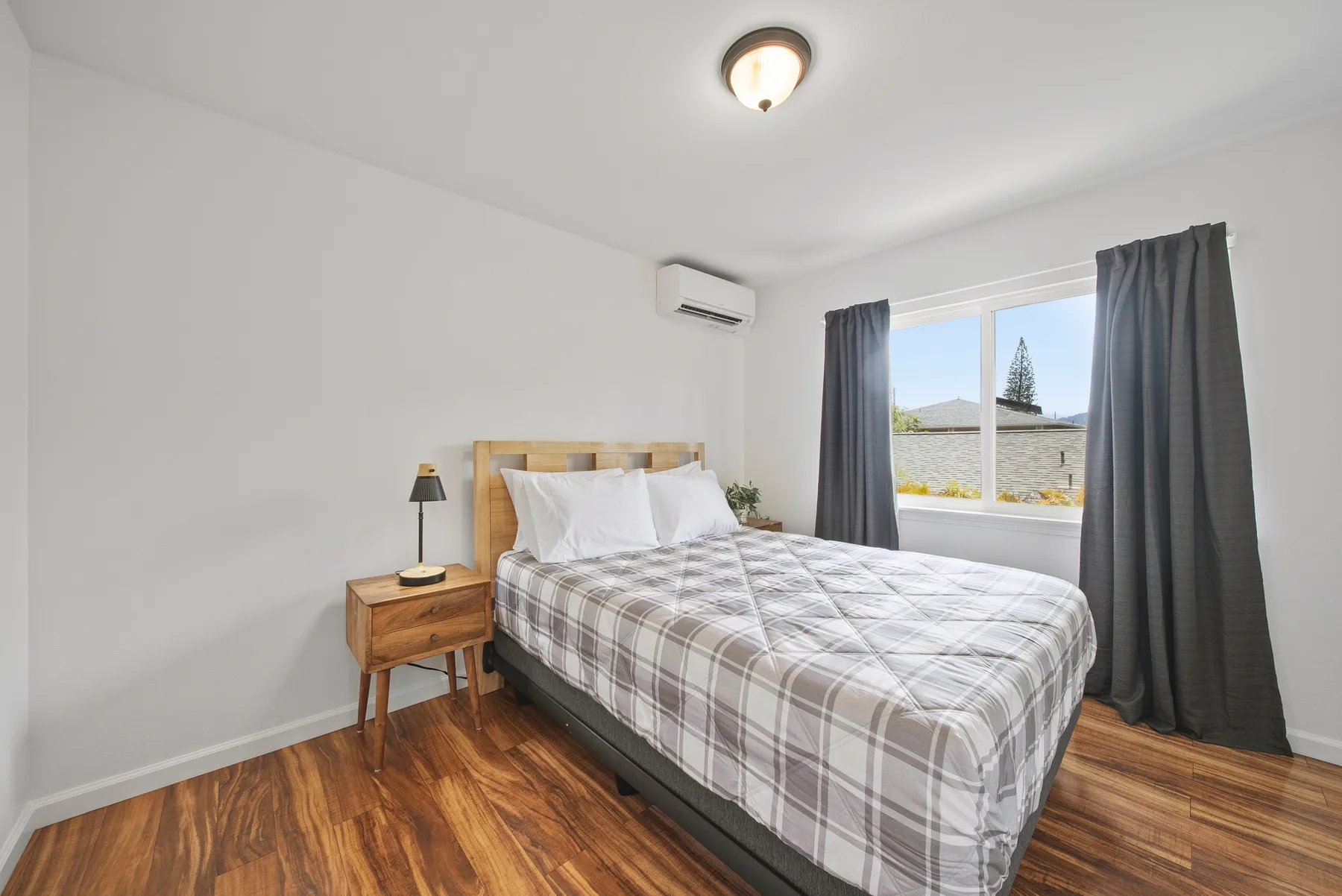 A bedroom with a bed beside a window framed by curtains.
