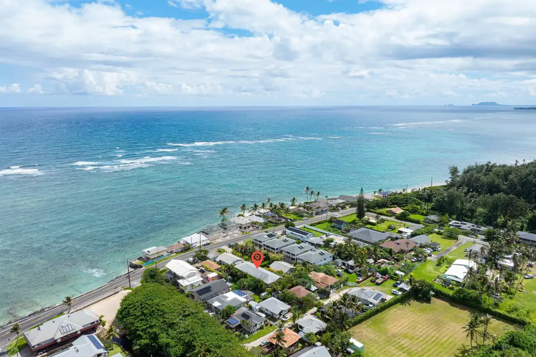 Aerial view of a coastal neighborhood beside turquoise ocean water.