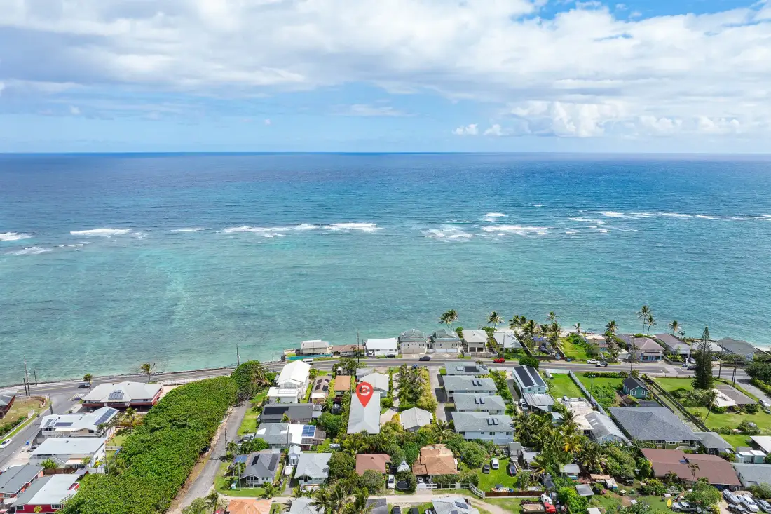 Aerial view of a coastal neighborhood beside a broad turquoise ocean.