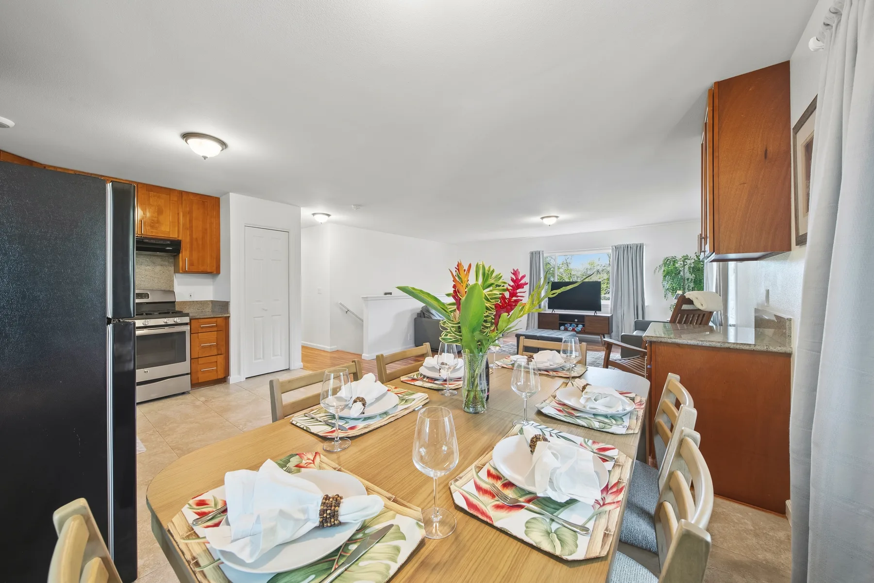 A dining area with a set table and an open kitchen in the background.