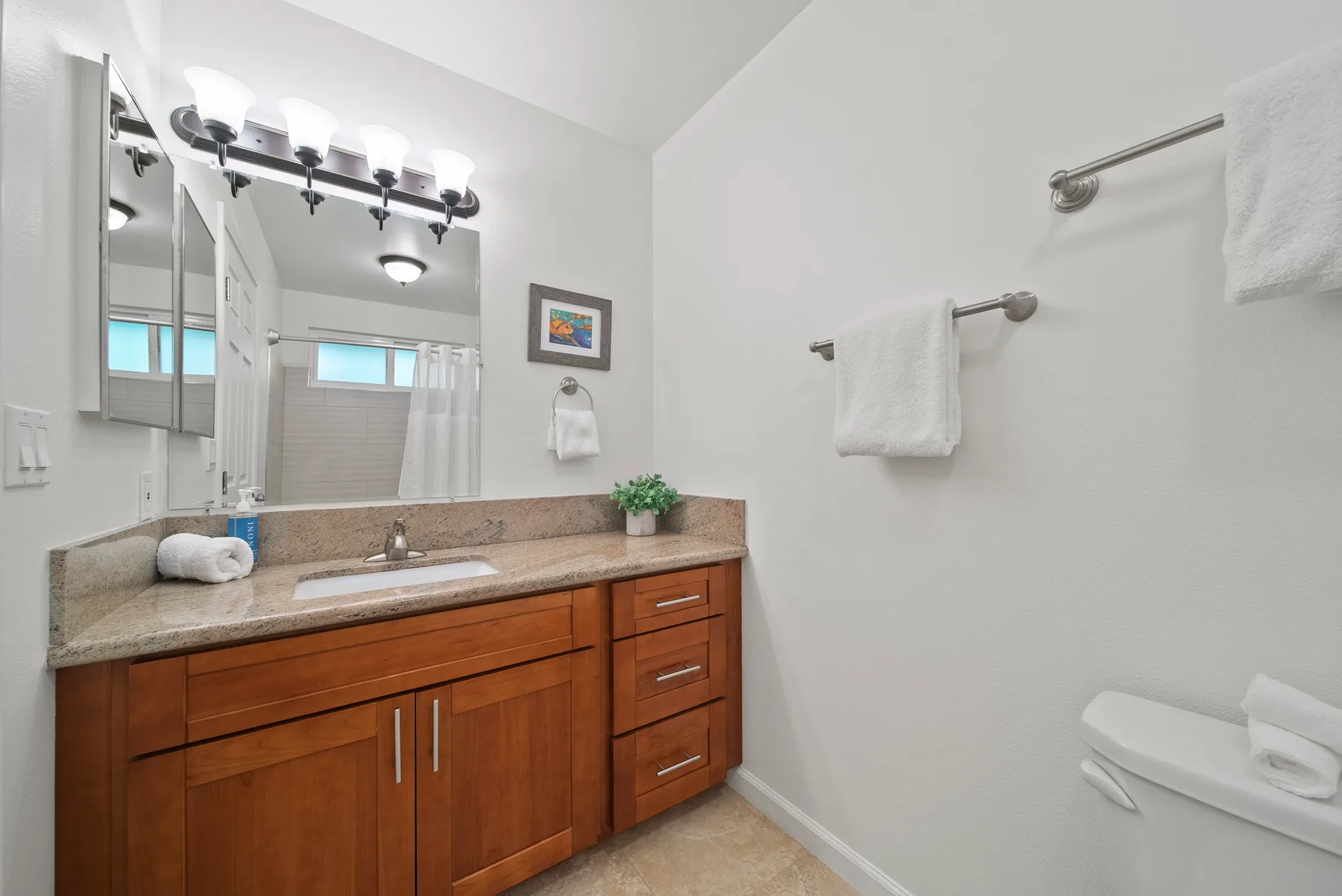 A bathroom vanity with a wide mirror and a towel bar on the wall.