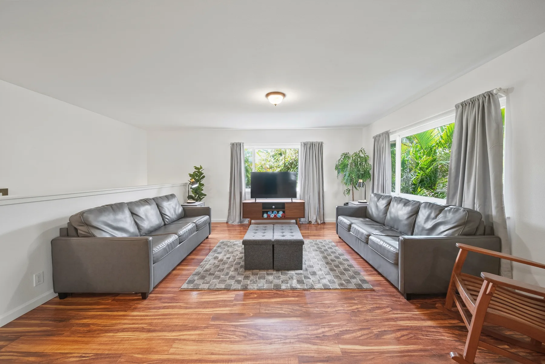 A living room with two seating areas facing a television and a patterned rug.