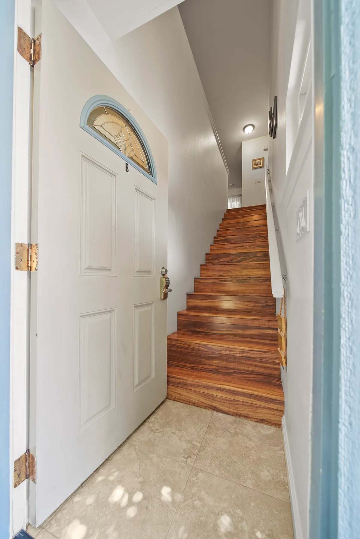 An entryway opens onto a wooden staircase, with a white paneled door beside it.