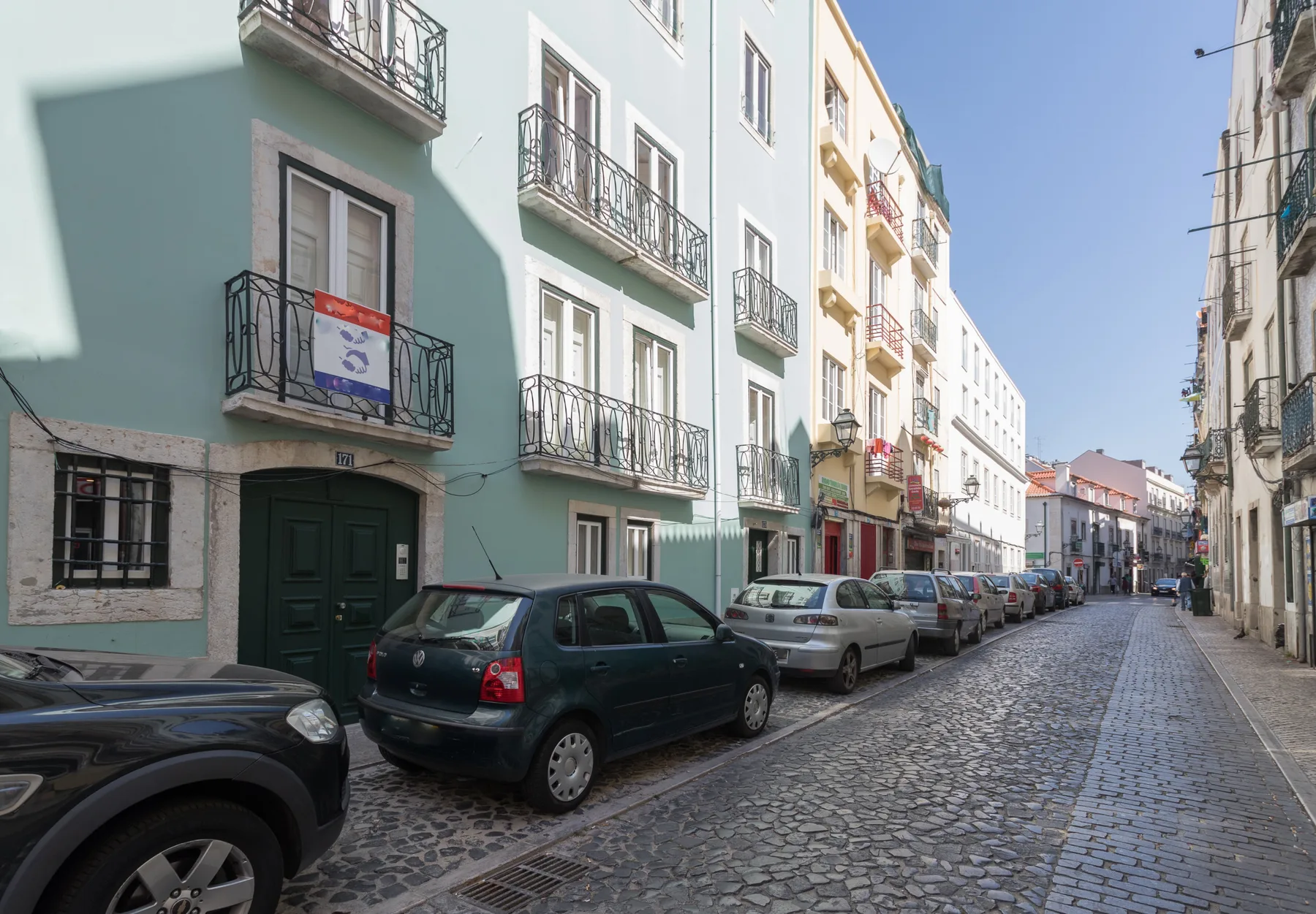 Una calle adoquinada bordeada de edificios coloridos y coches estacionados.