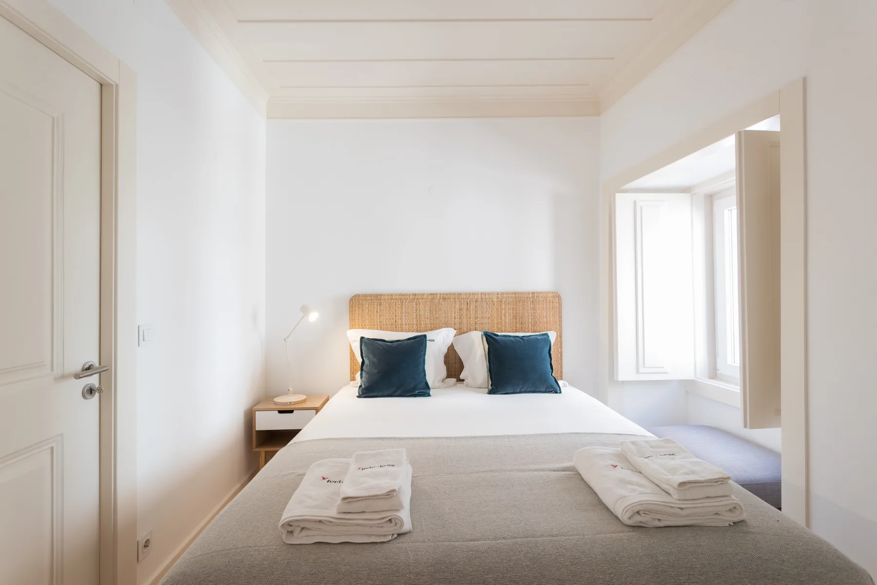 Un dormitorio luminoso con una cama doble y dos toallas dobladas.