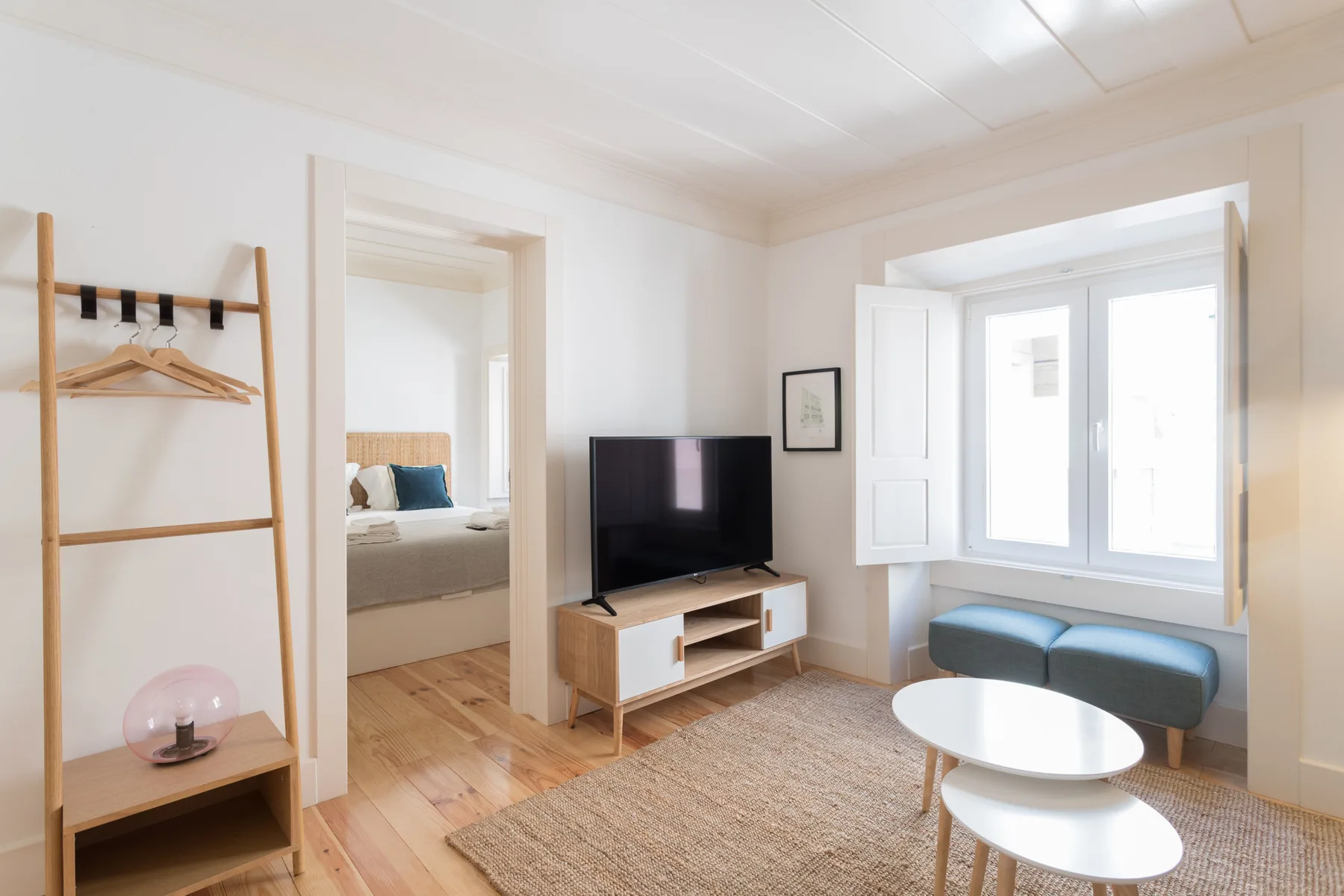 Una sala luminosa con televisor, asientos y una ventana grande.