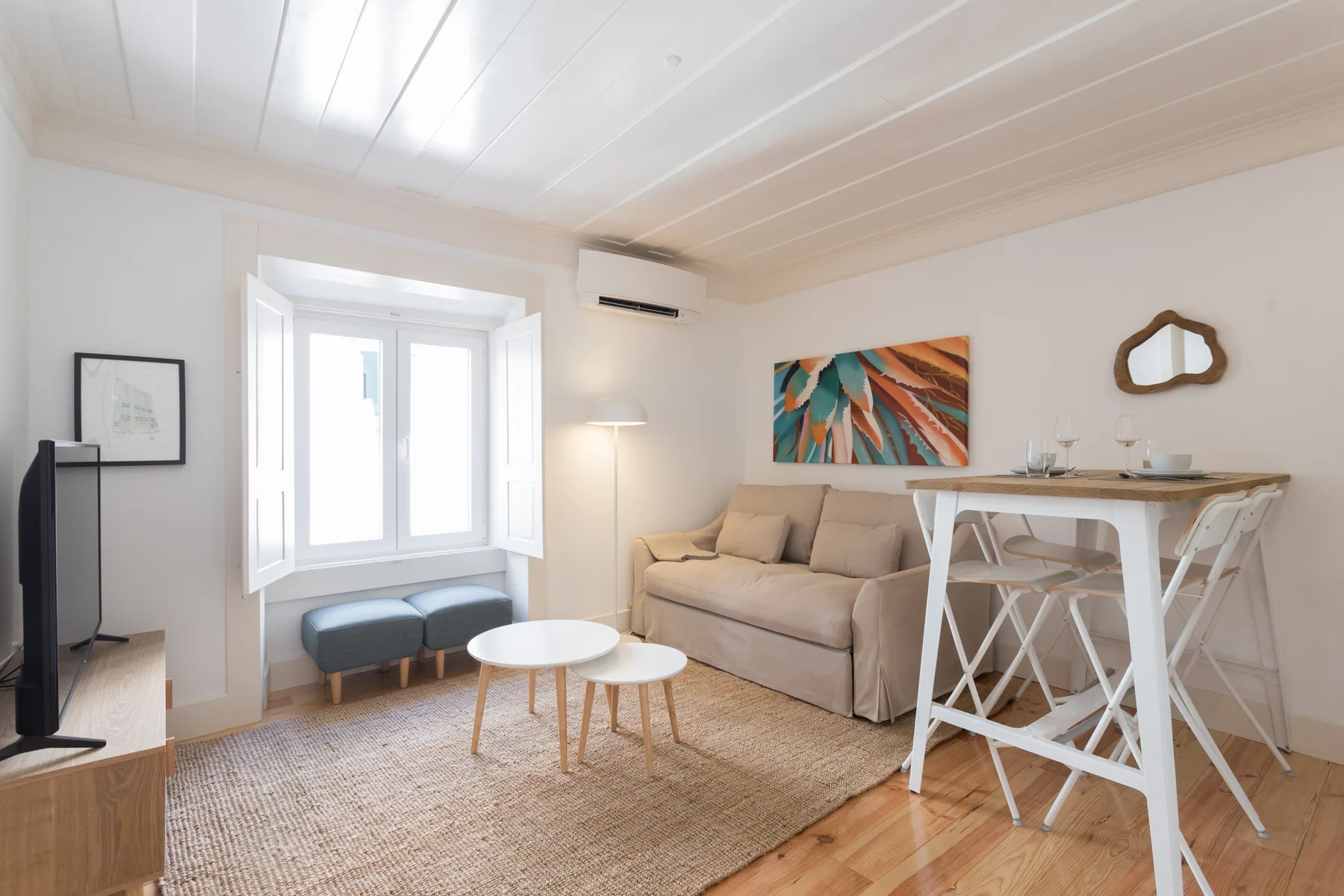 Una sala luminosa con una zona de estar beige y una mesa de comedor junto a la ventana.