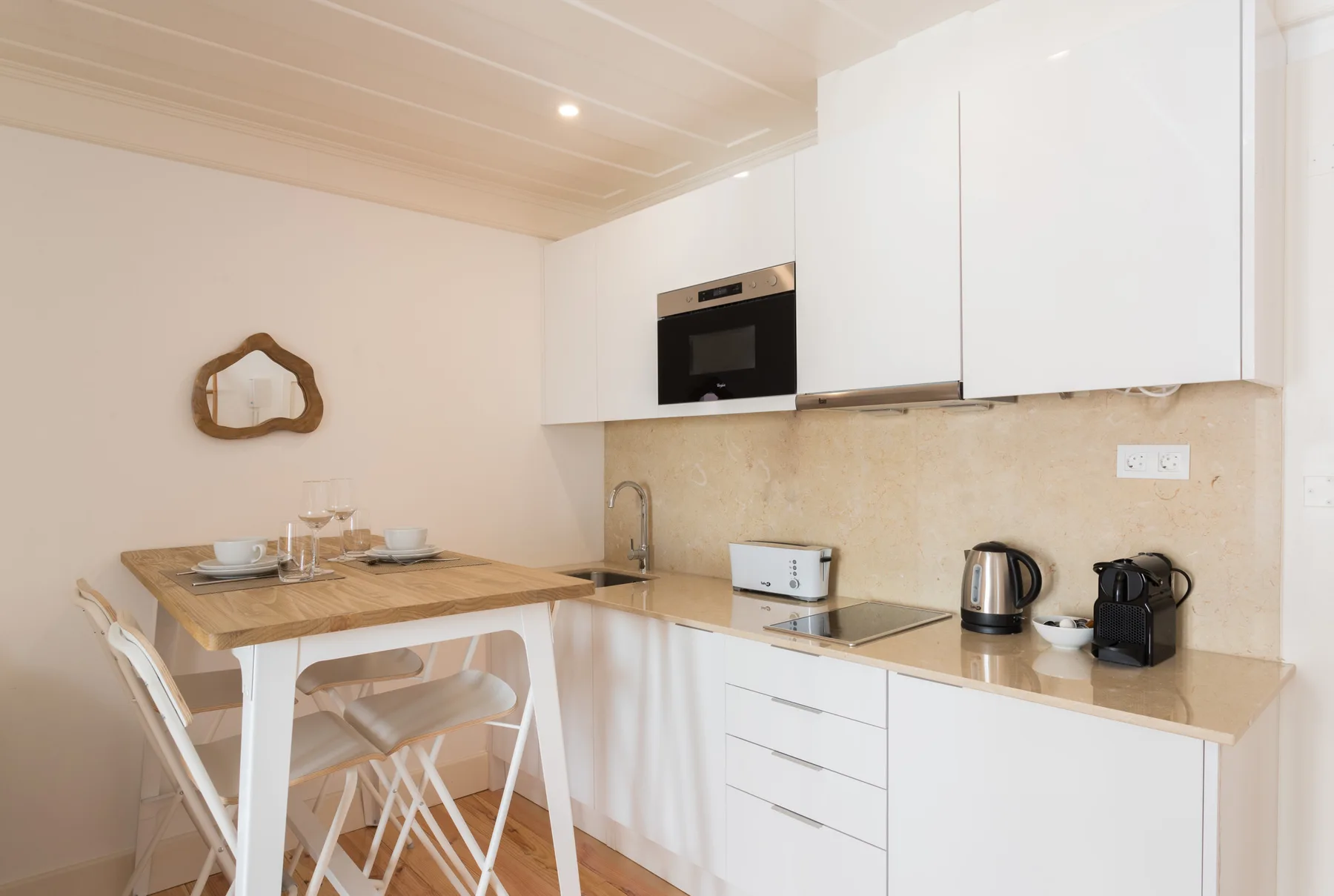 Una cocina compacta con zona de comedor, encimera, electrodomésticos y una mesa pequeña.