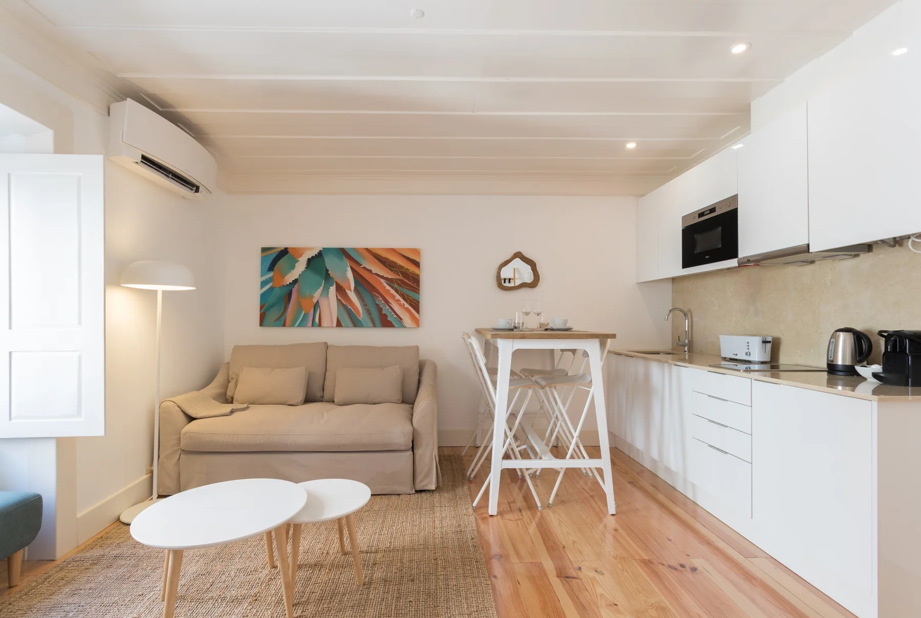 Una sala de estar con un sofá y una cocina compacta.